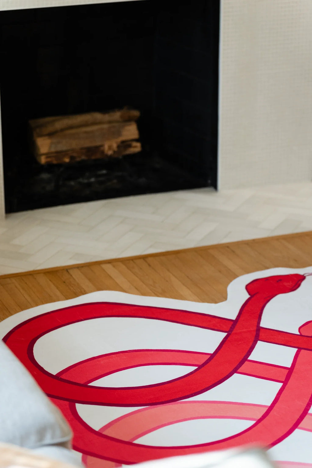 Corner crop of the abstract loop rug in front of the fireplace, with rounded red bands and white sections