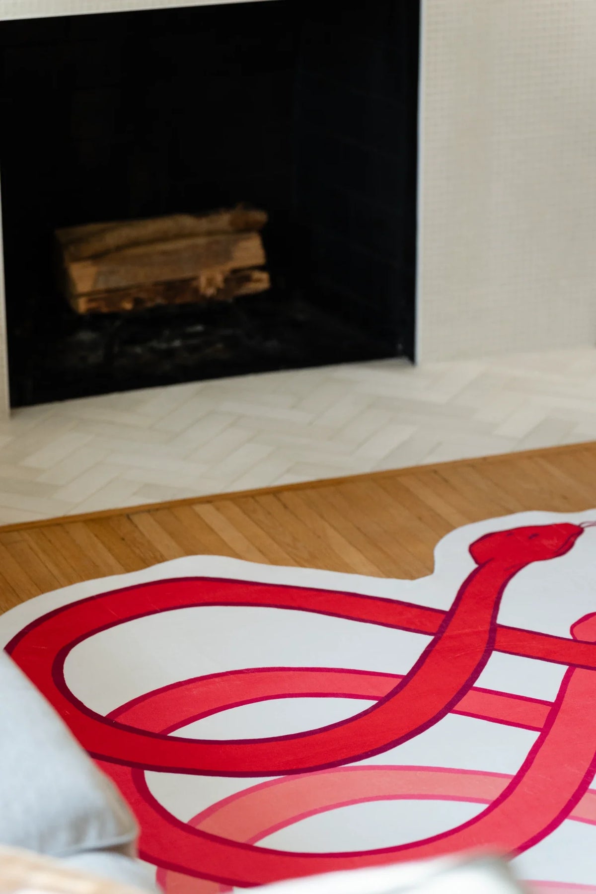 Corner crop of the abstract loop rug in front of the fireplace, with rounded red bands and white sections