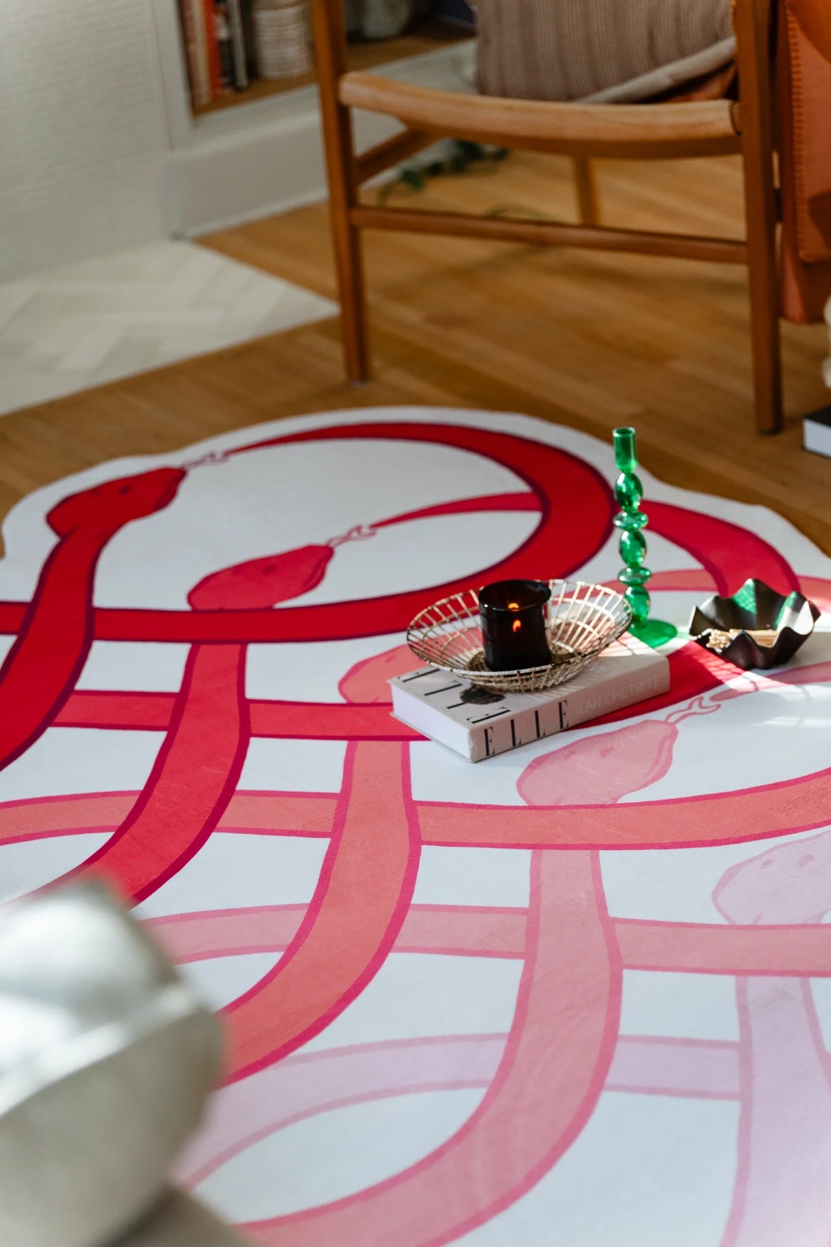 Close up of the red snake motif rug beside a tray, with looping curves repeated in a symmetrical pattern