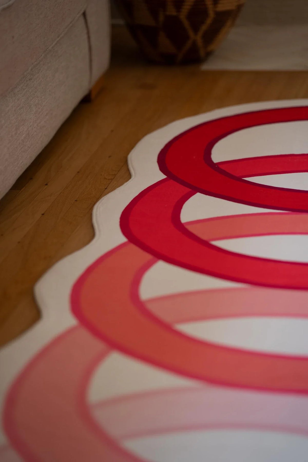 Partial crop beside the sofa, showing the outer edge of the red loop snake rug and white contour bands