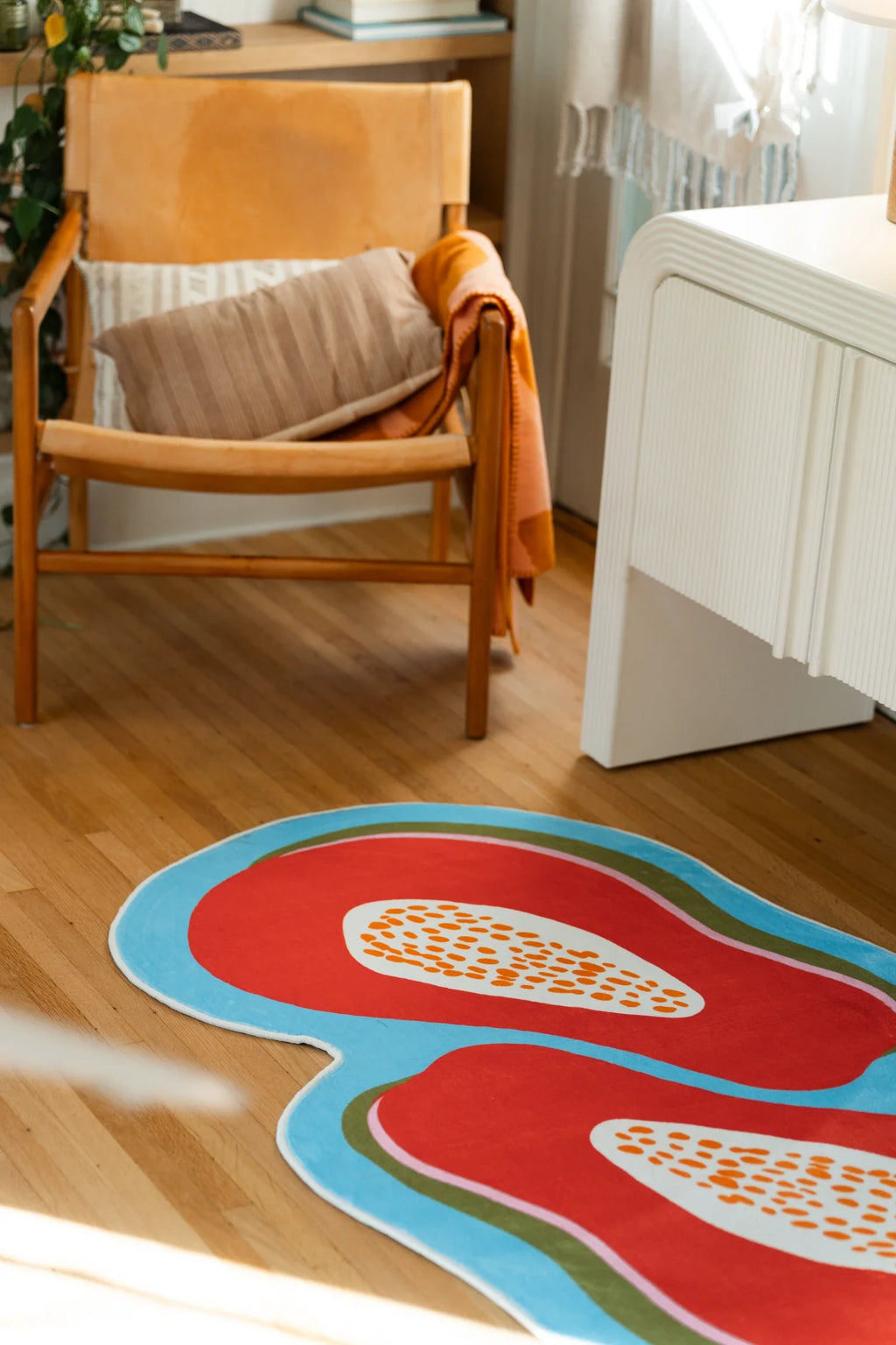Close view of the papaya rug beside a wood chair, showing two sliced fruit forms with pale seed centers