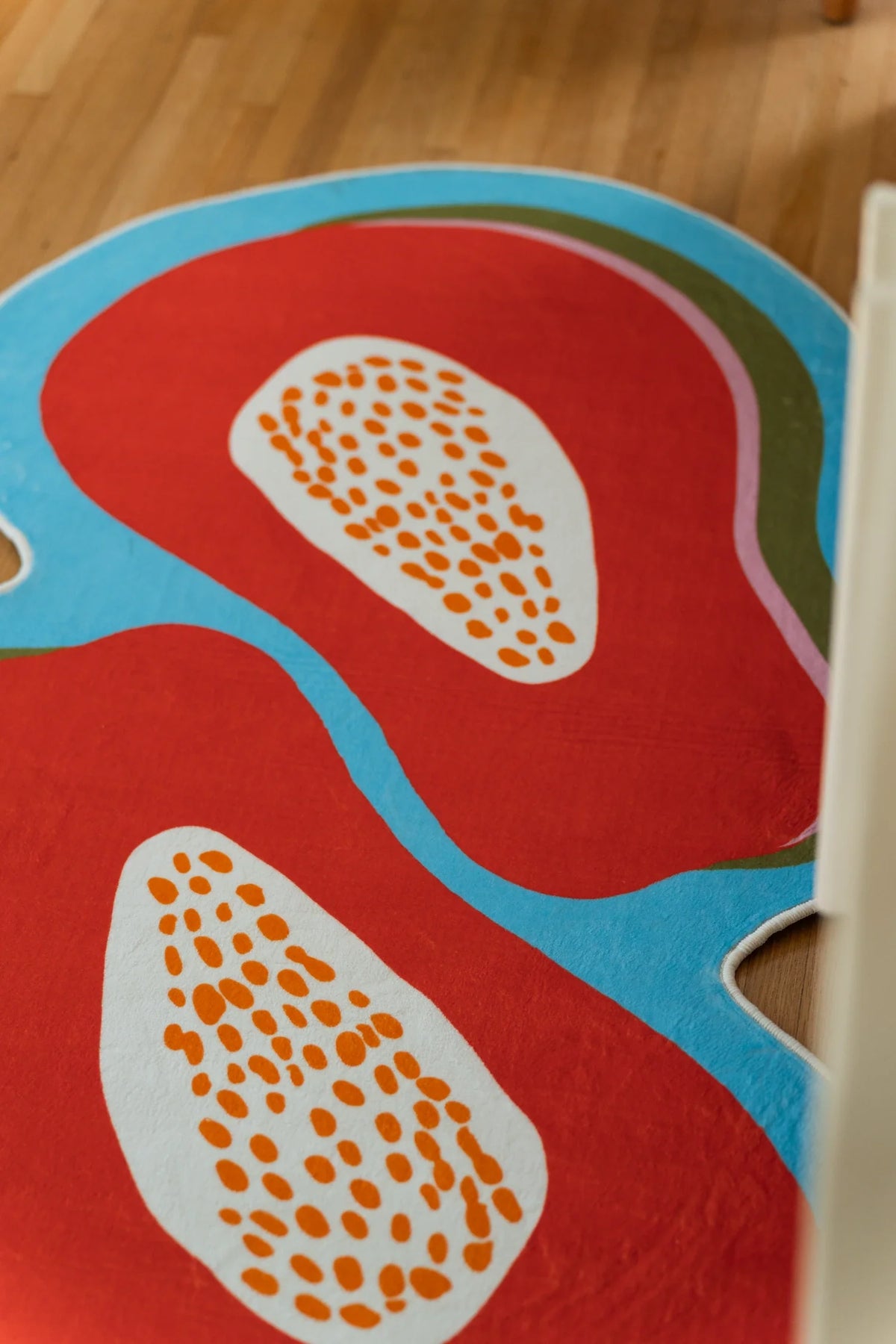 Close up of the irregular papaya rug showing two orange fruit halves and cream seed details