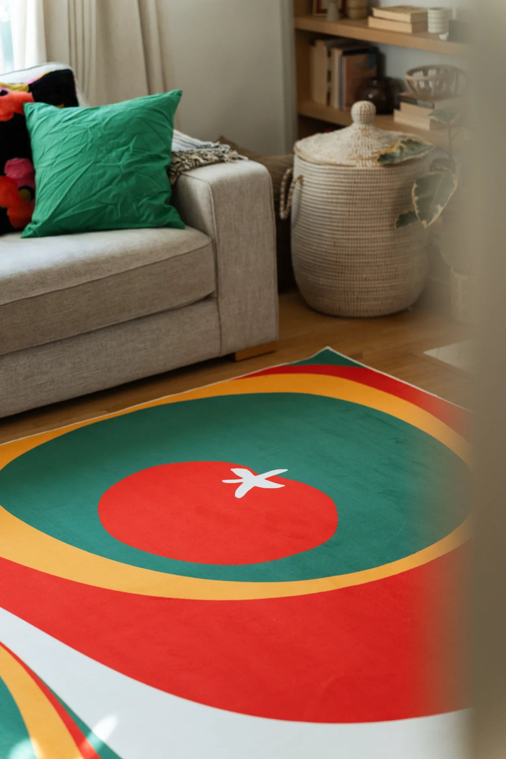 Olive and red rug near a beige sofa with a green pillow nearby, showing a white seed star and curved bands