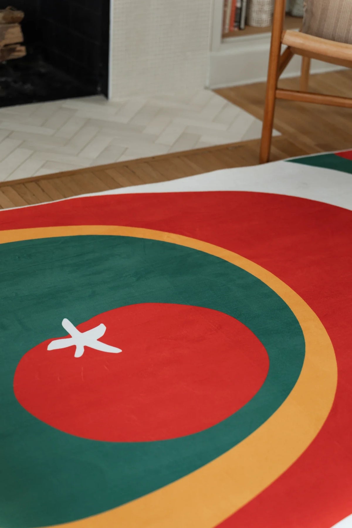 Olive and red rug near a fireplace and wood chair, showing a red circle with layered green and white bands