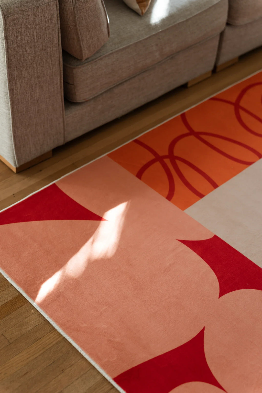 Partial corner view under the sofa with sunlight across a pink block and red star shape