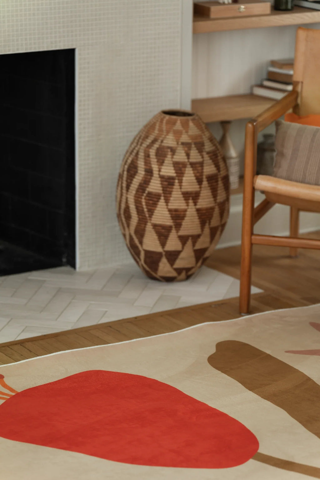 Corner detail near the fireplace and woven basket, showing a red petal block and curved tan leaf shape