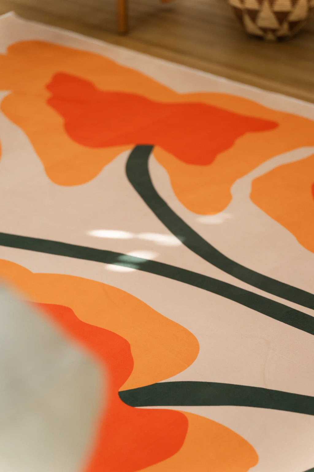 Corner detail of the rug showing dark green stems crossing between orange and peach flower forms