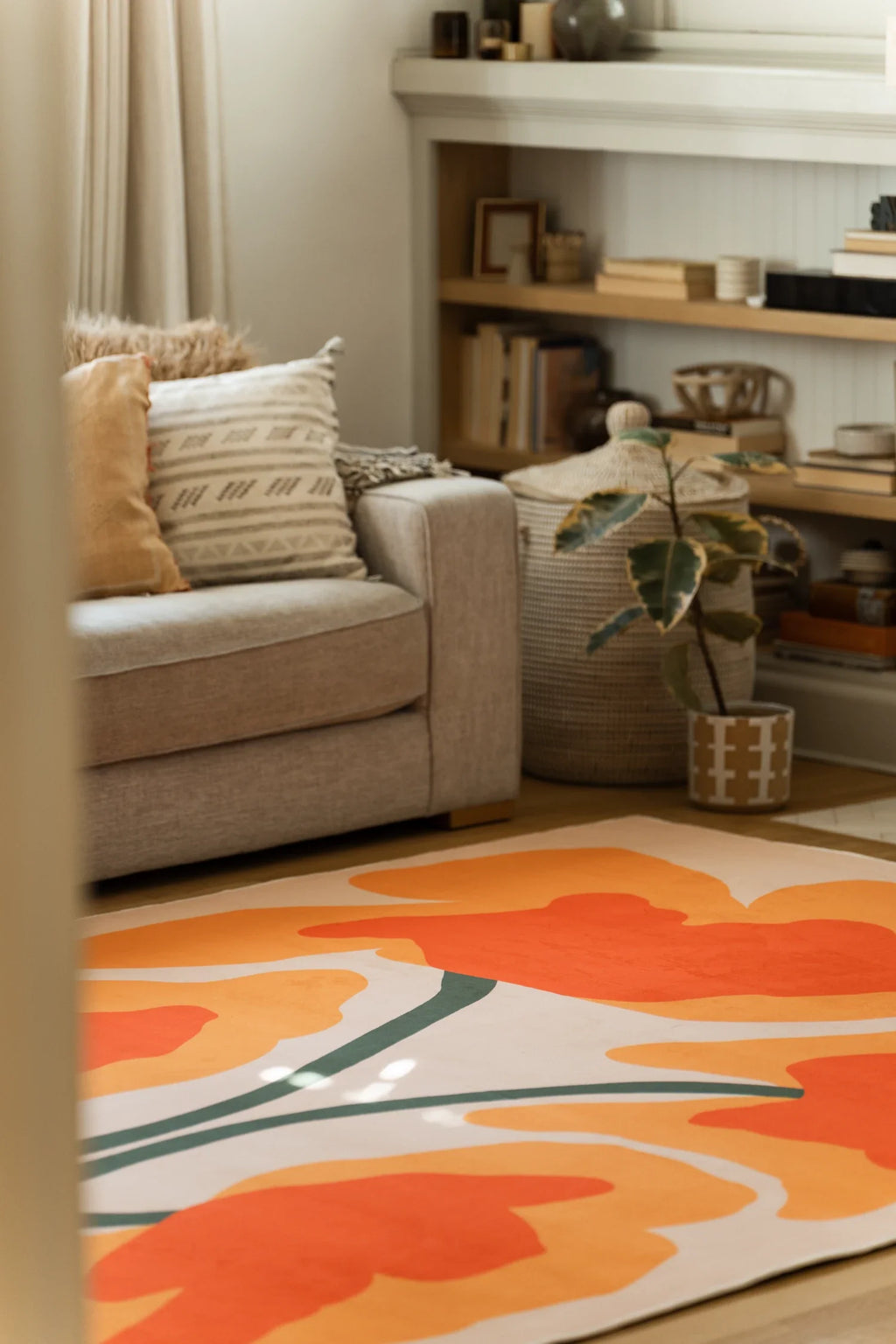 Rug detail near a low shelf and potted plant, showing free form orange petals and flowing green lines