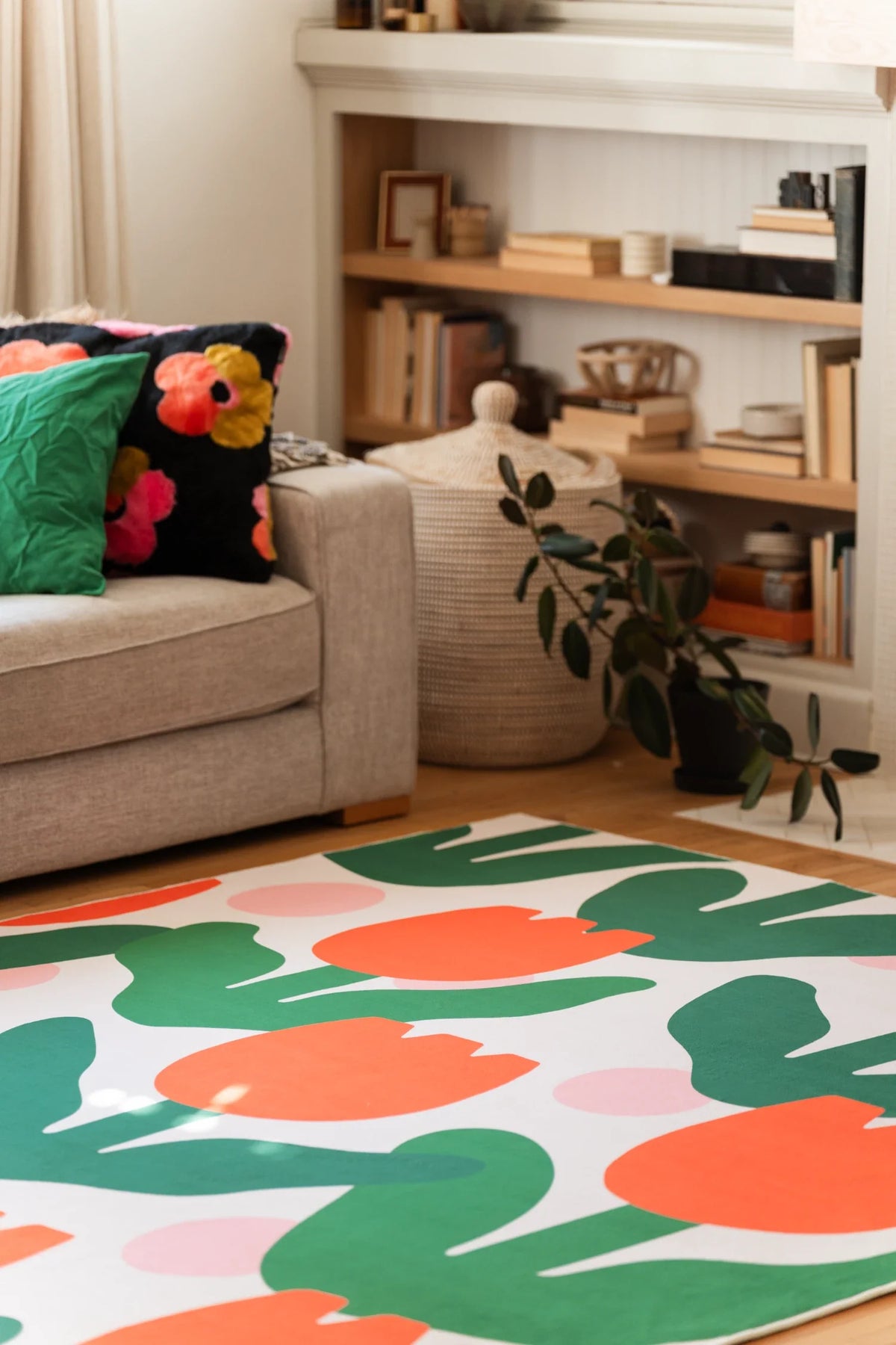 Partial view of the rug beside a beige sofa and plant, with rounded tulip heads and layered leaf forms