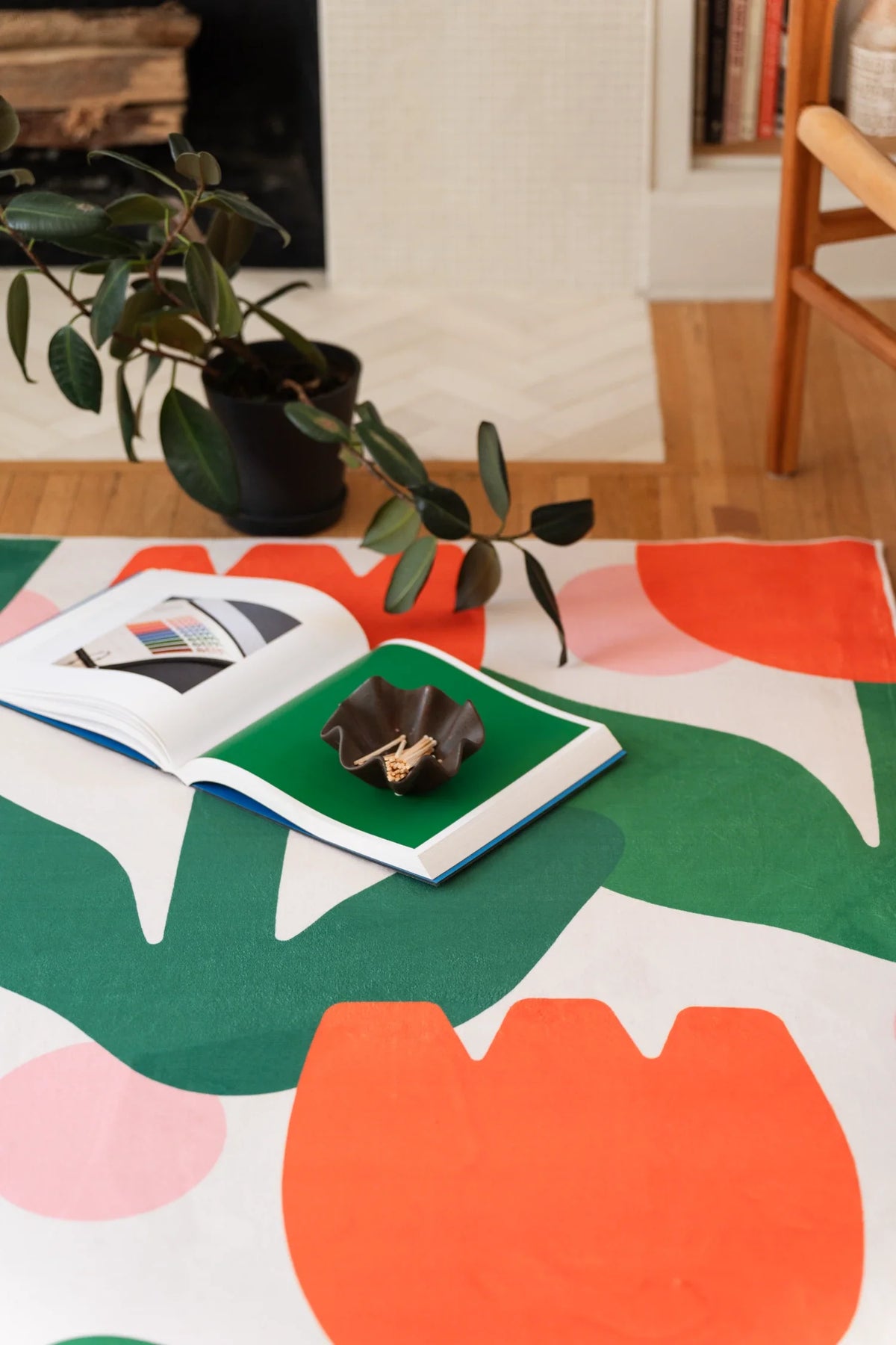 Close detail of the floral area rug with oversized tulip forms spreading across the floor beside a leafy branch