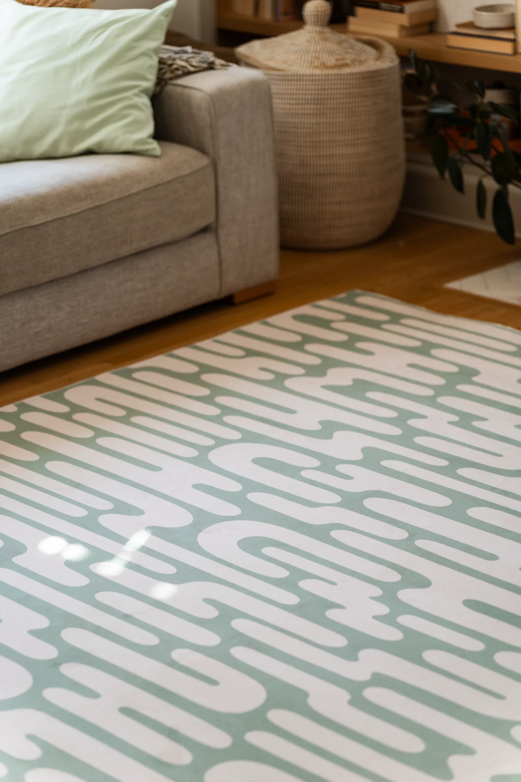 Patterned rug on a wooden floor with a couch and decorative items in the background