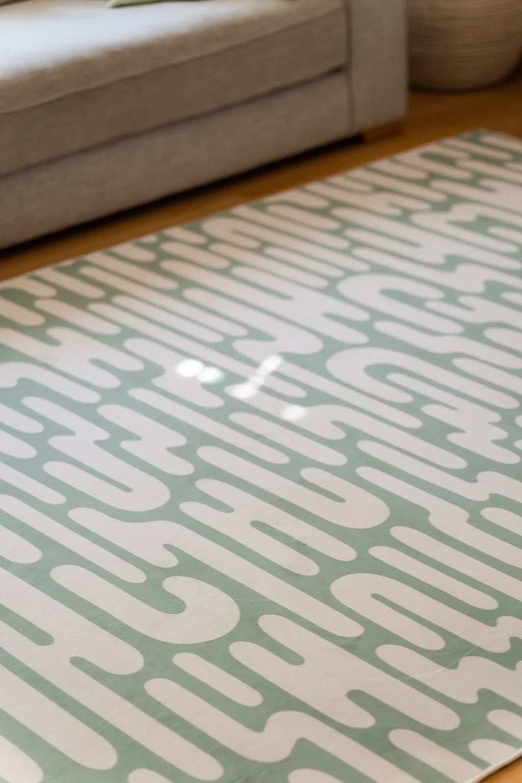Detail of the wavy area rug with sunlight across the surface, highlighting the flowing green and cream lines