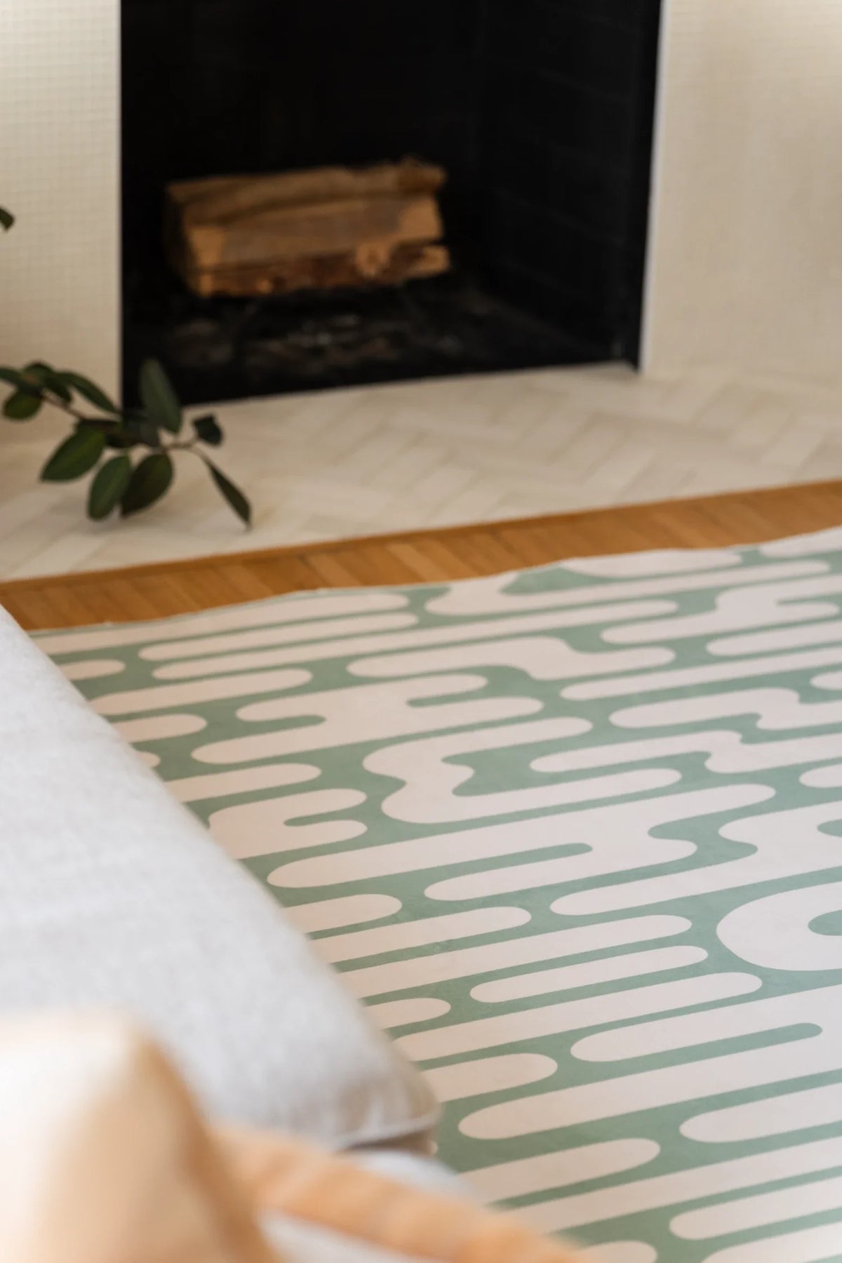 Brown abstract wavy area rug centered between the sofa and fireplace, with looping cream pathways on a deep rust ground
