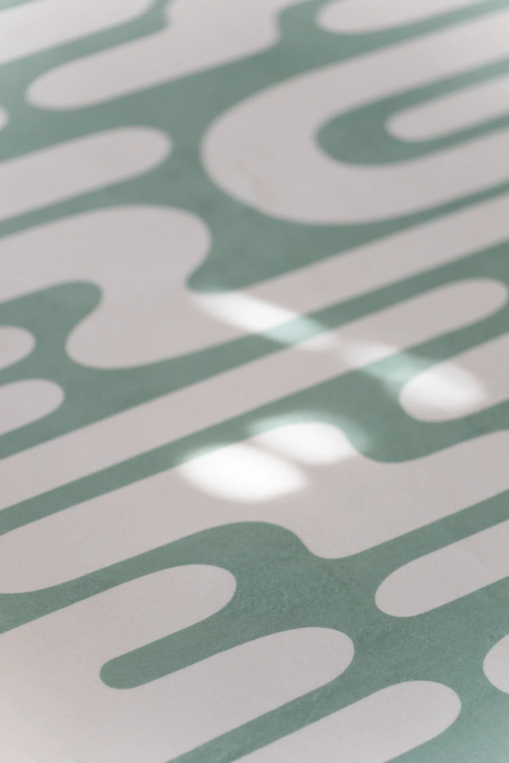 Close up of the green Abstract Wavy Area Rug with curved lines and soft sunlight across the surface