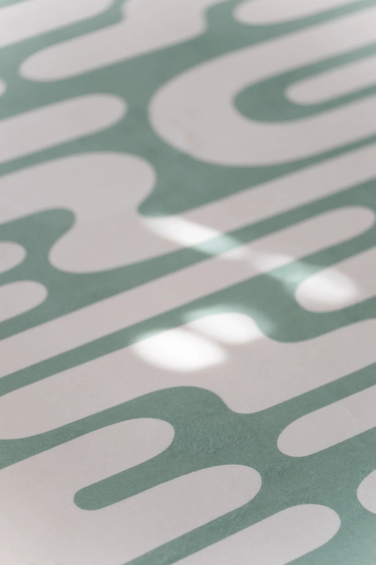 Close up of the green Abstract Wavy Area Rug with curved lines and soft sunlight across the surface