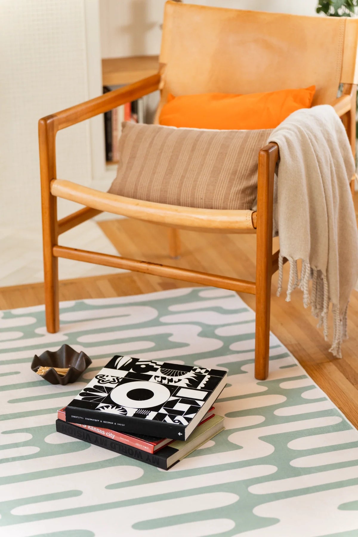 Abstract wavy rug tucked under a neutral sofa, with looping pale pathways across the green surface