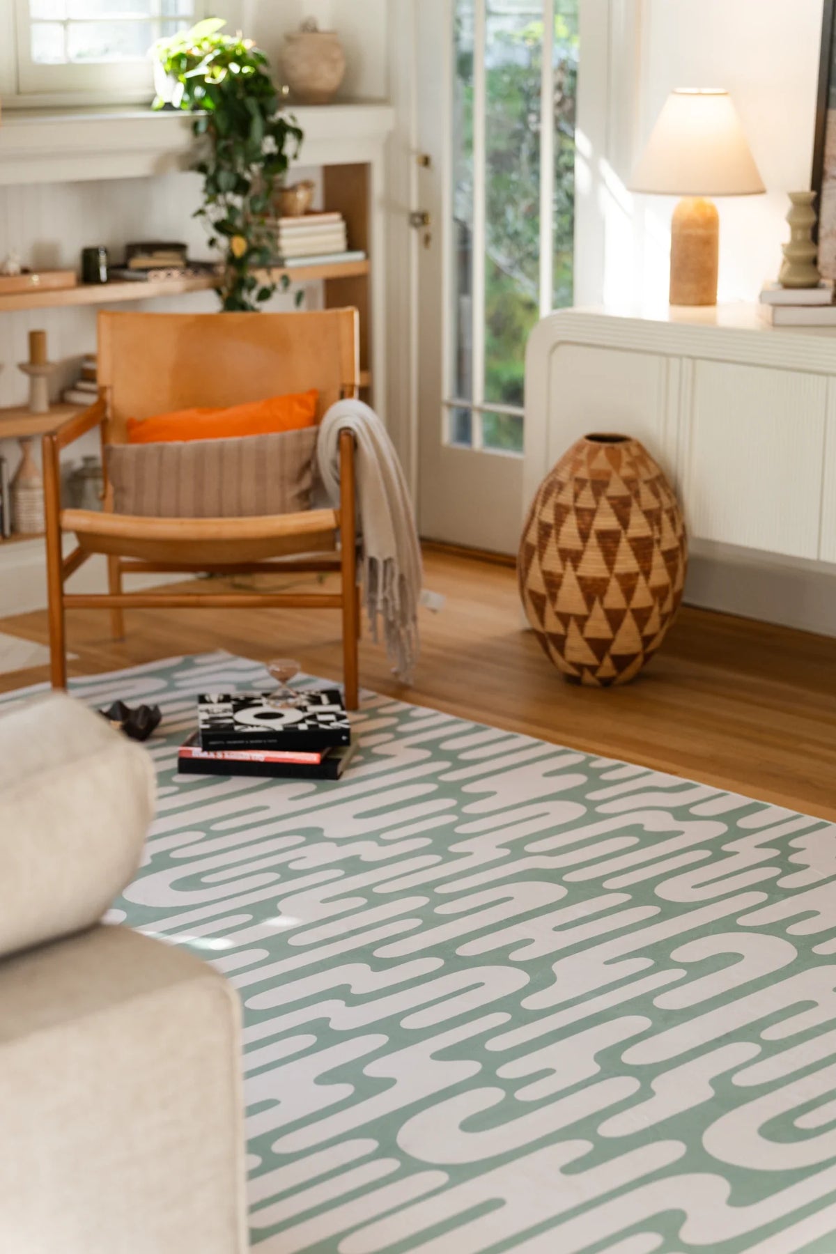 Green Abstract Wavy Area Rug in a cozy seating corner with a wood chair, soft window light, and warm wood tones