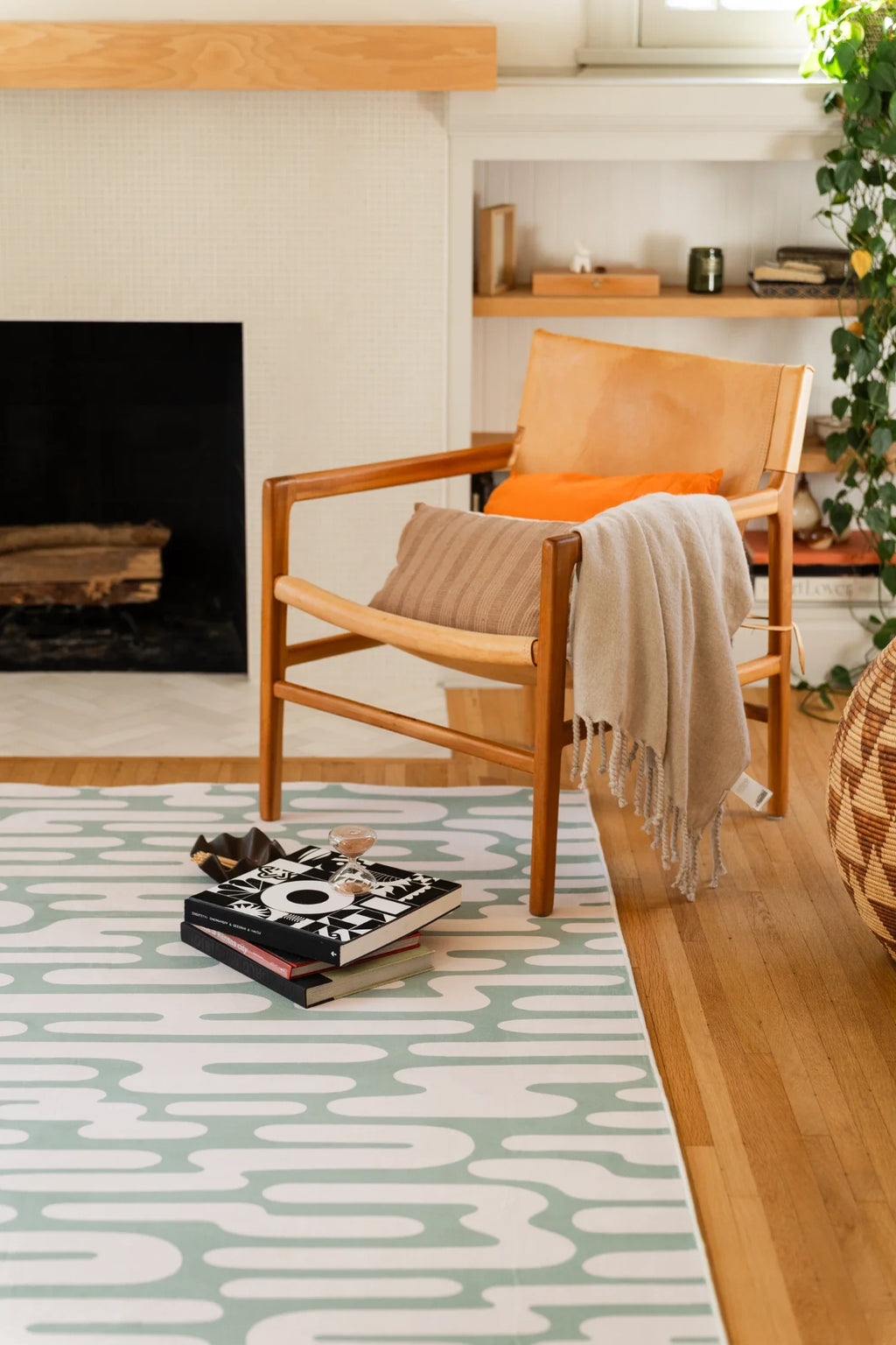 Green Abstract Wavy Area Rug beside a wood framed chair and stacked books in a warm modern living room