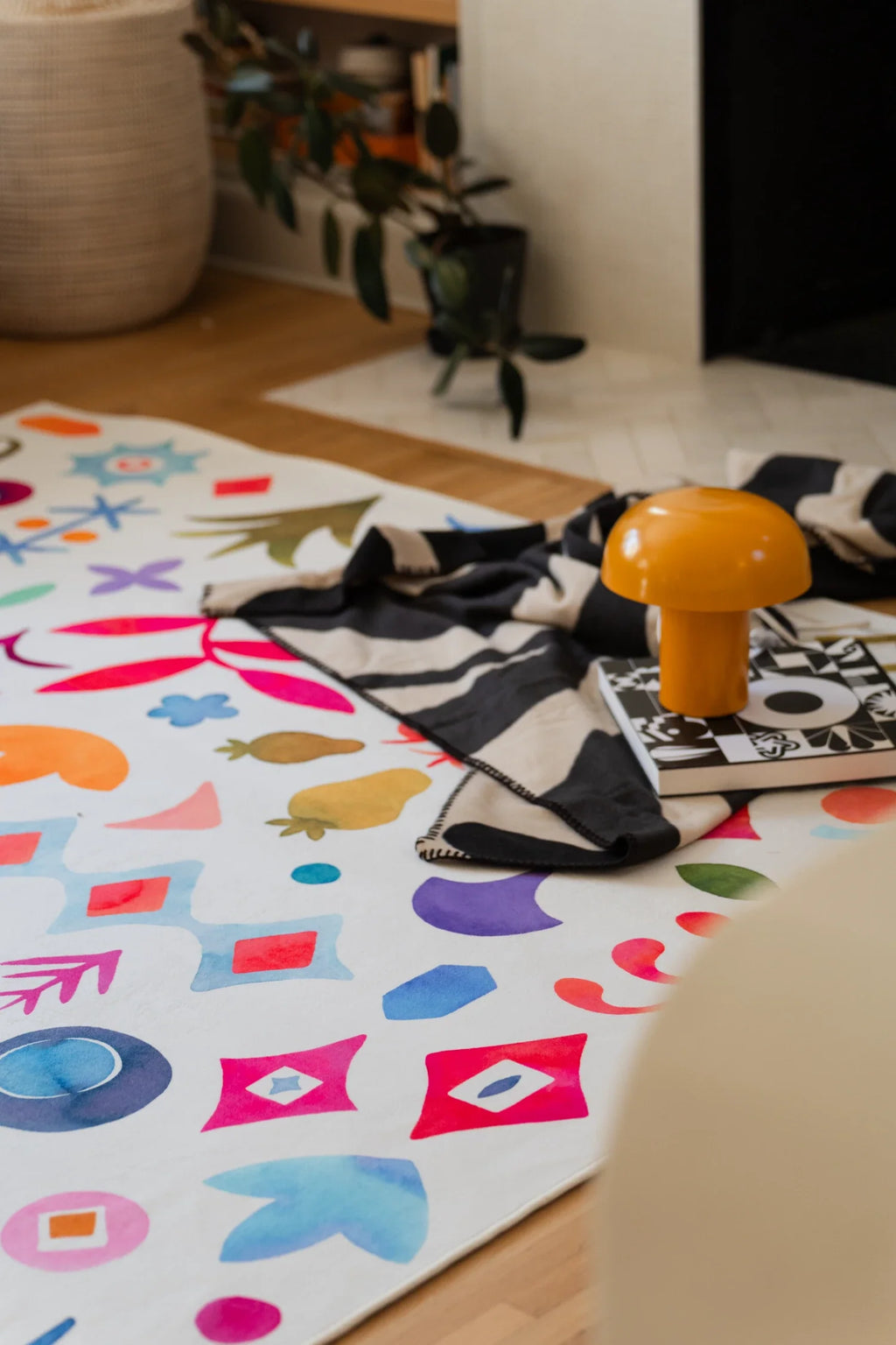 Graphic pattern area rug near a woven basket and stacked books, with bright multicolor icons spread across a white background
