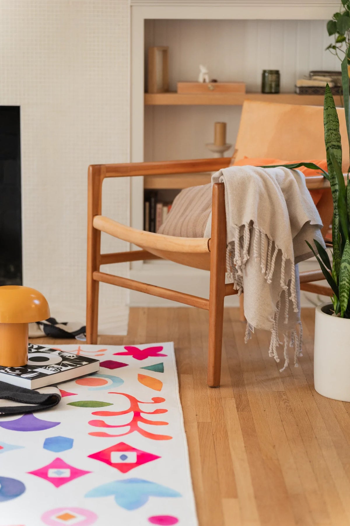Partial view of the colorful area rug beside a wood chair and open shelving, showing scattered nature symbols on a white field