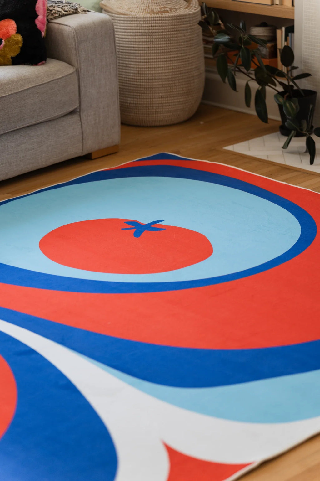 Close up of the blue and red Tomato Twist rug with a pale blue circle, red center, and blue stem detail
