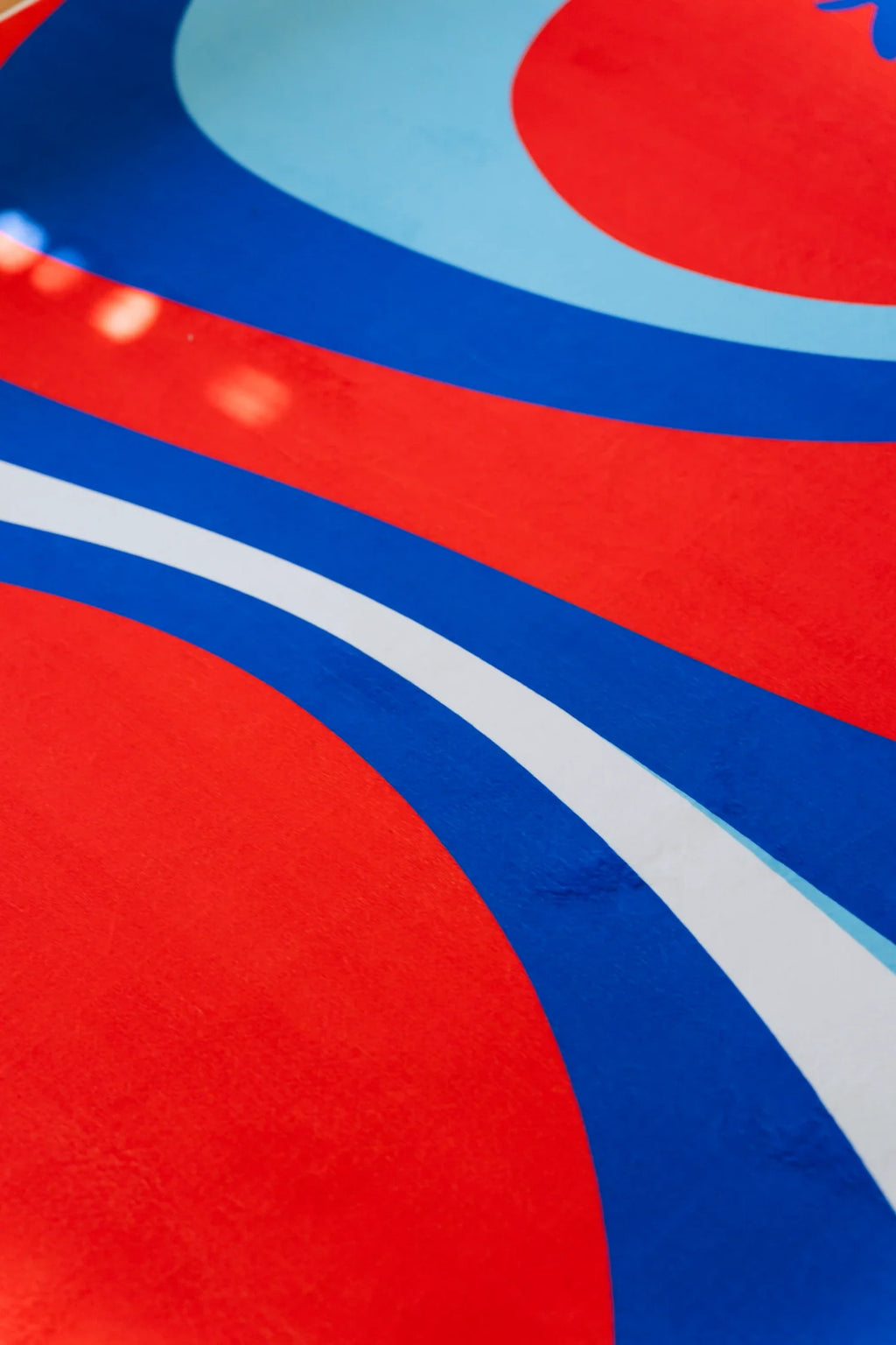 Detail of the blue and red rug showing broad red curves, royal blue bands, and a pale blue border