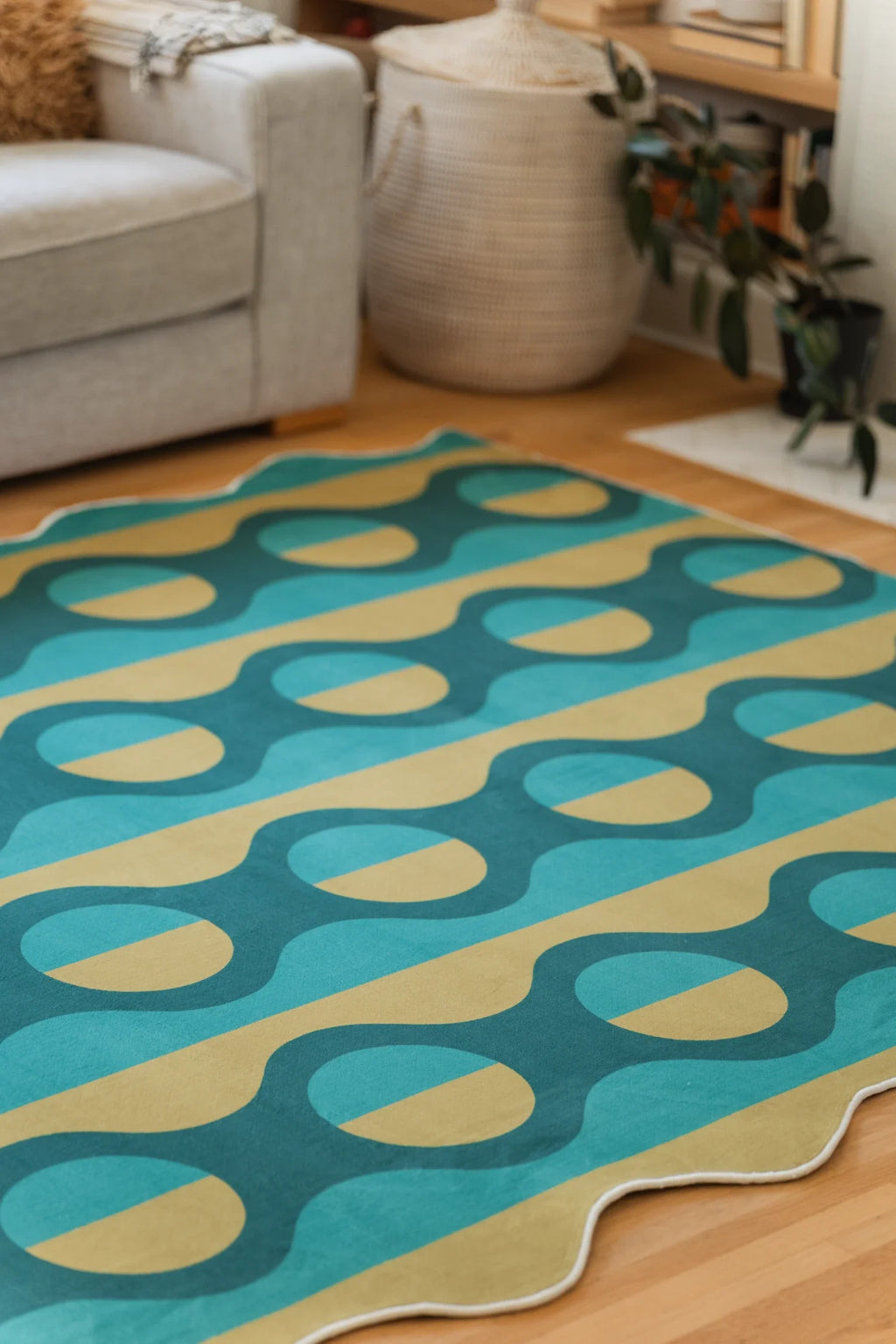 Partial view of the green striped rug beside a beige sofa and woven basket, with repeating mustard oval shapes