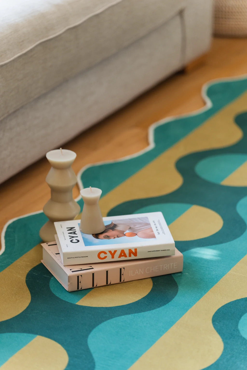 Green and mustard striped rug beside stacked books and a wood toy, with graphic oval shapes on the surface