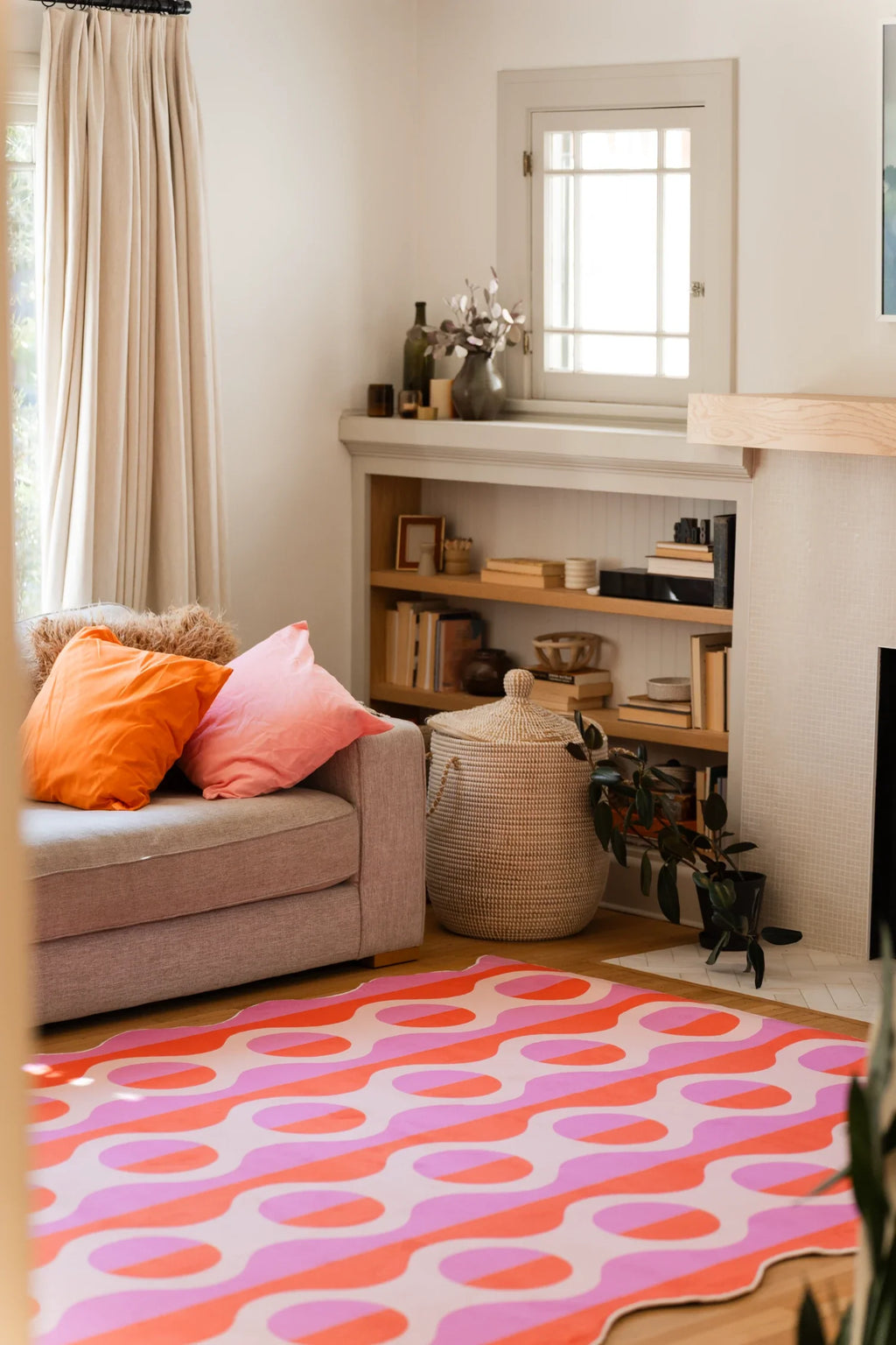 Pink striped rug in a bright corner beside a beige sofa and low shelf, with repeating orange oval forms