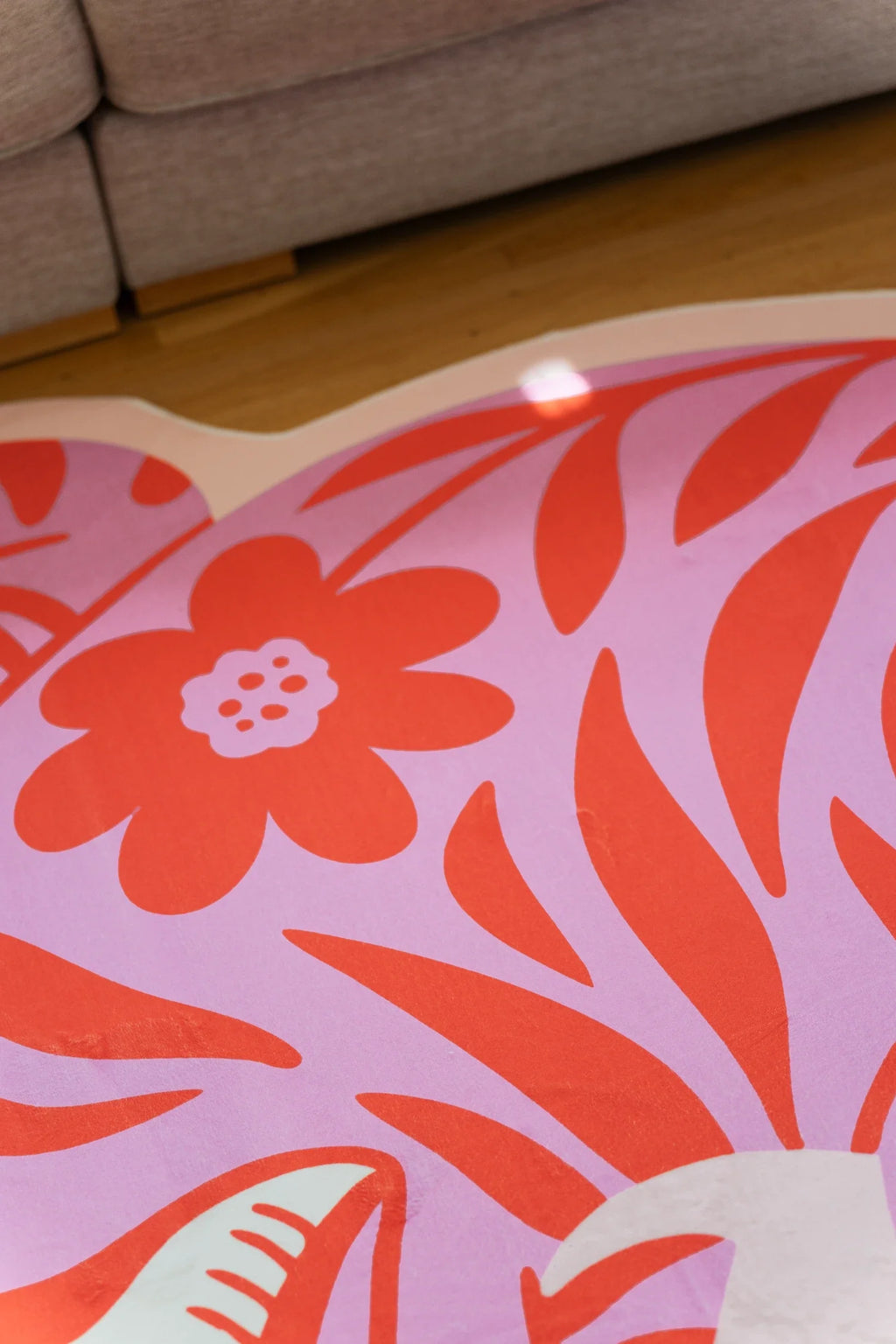 Close up of the pink tiger rug showing a coral flower motif set into the curved body on a light wood floor