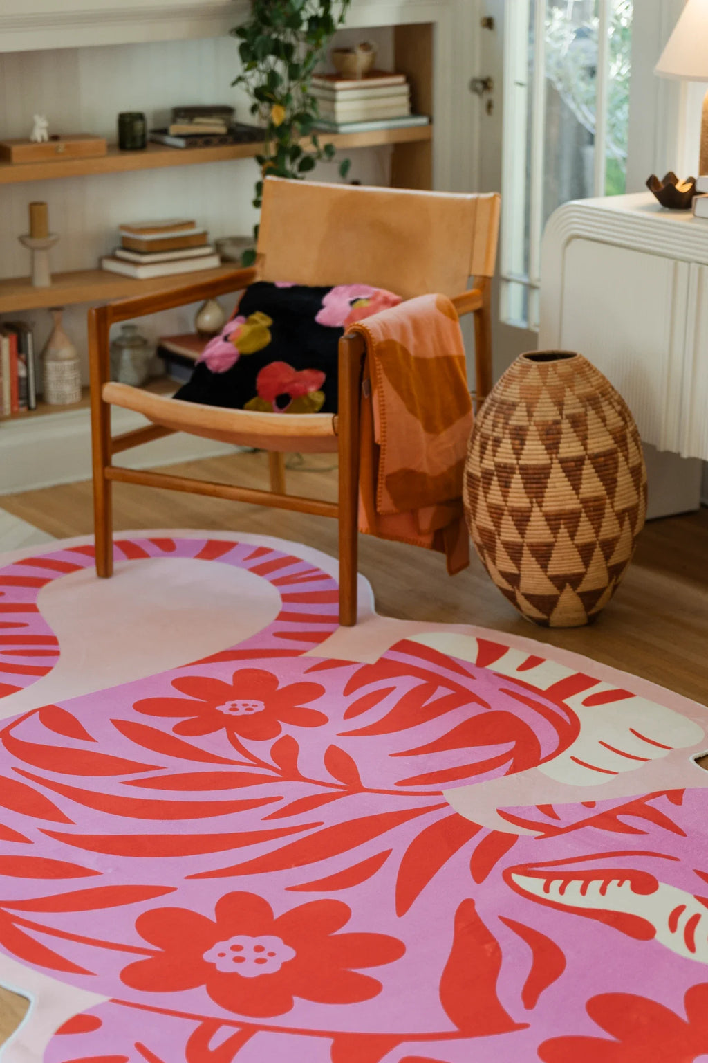 Close detail near the wood chair, with the tiger rug's floral face motif and layered coral stripes across the body