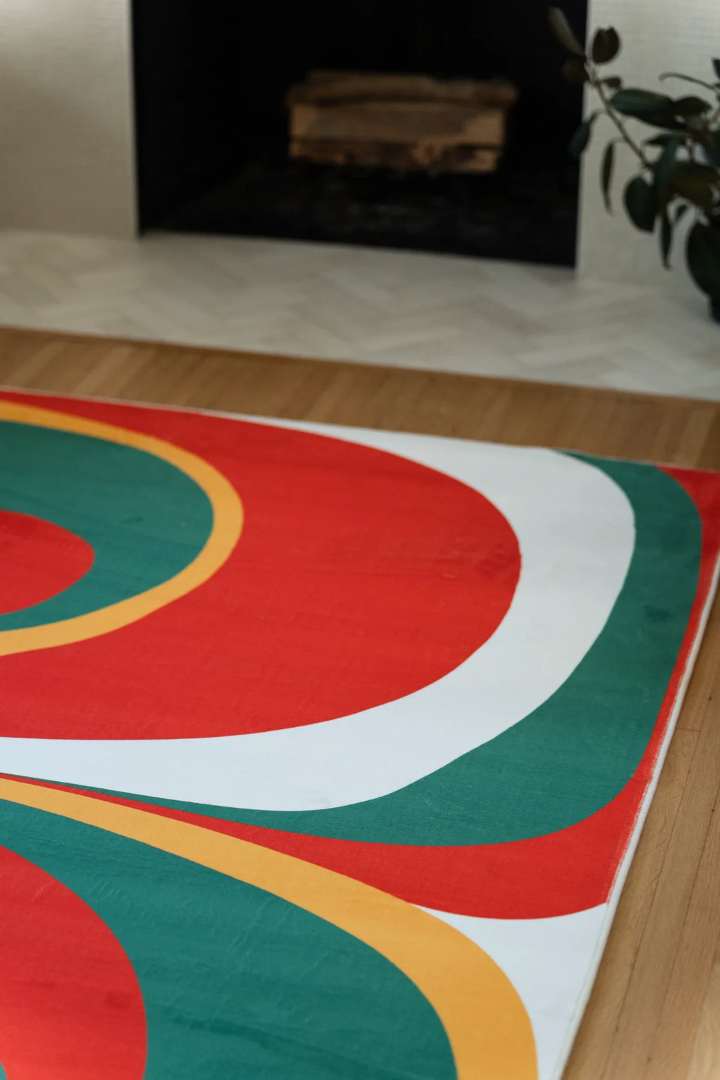 Partial view of the olive and red Tomato Twist rug near the fireplace, showing rounded red and green forms