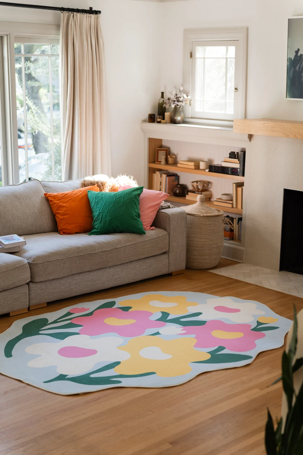Irregular shaped floral rug beside a beige sofa in a modern living room, with layered pastel blooms and curved green stems