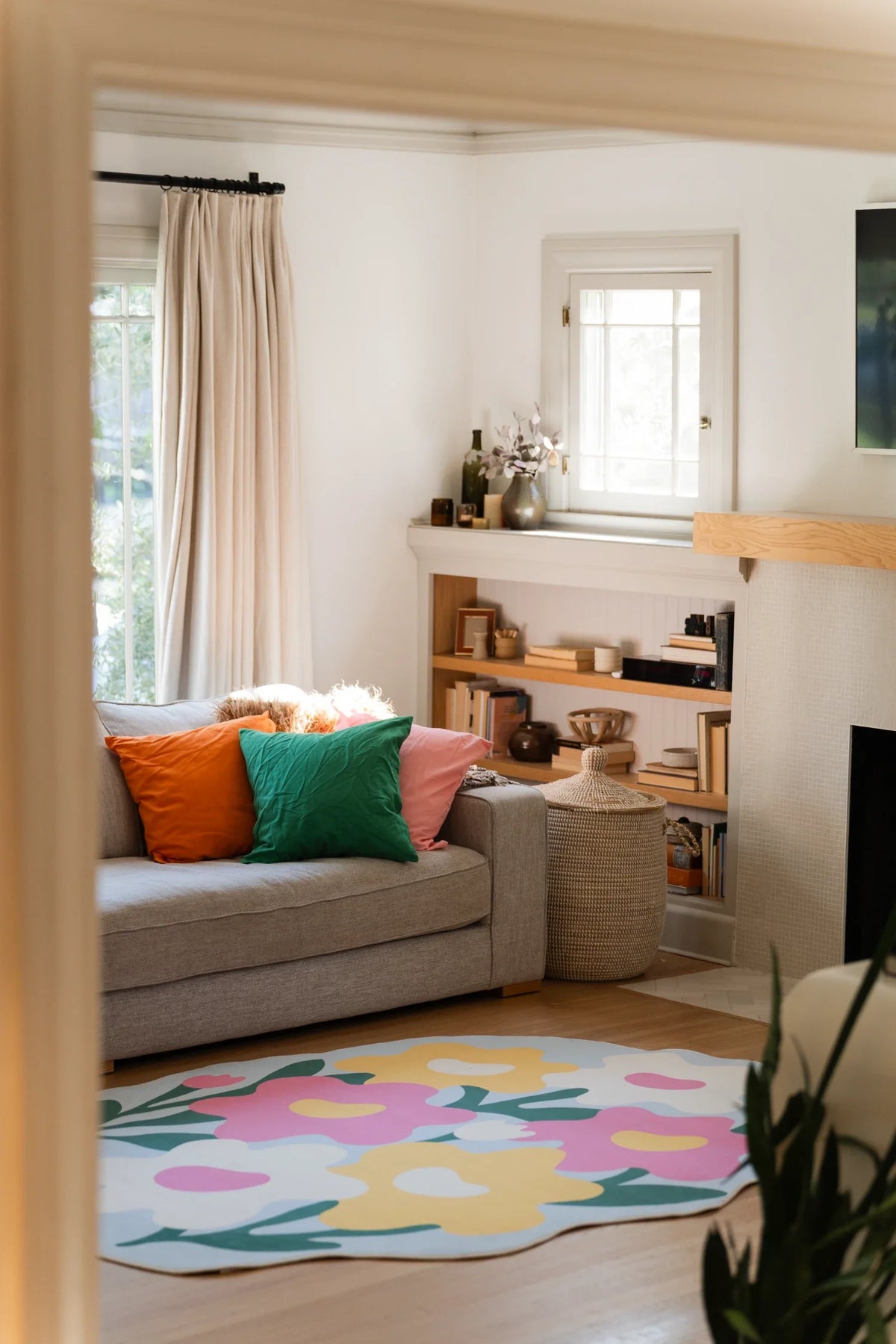 Colorful irregular shaped rug in a cozy living room beside a beige sofa, with oversized flowers on a soft blue ground