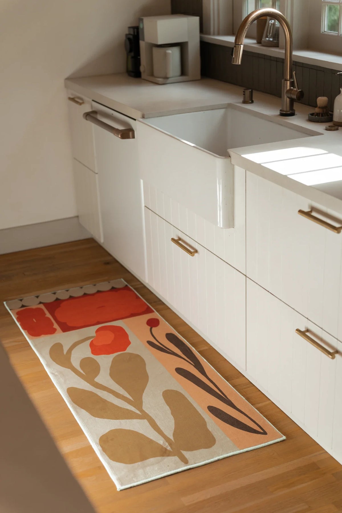 Partial view of the Rust Red Vintage Patchwork Floral Rug beside a white sink cabinet, showing graphic leaf shapes