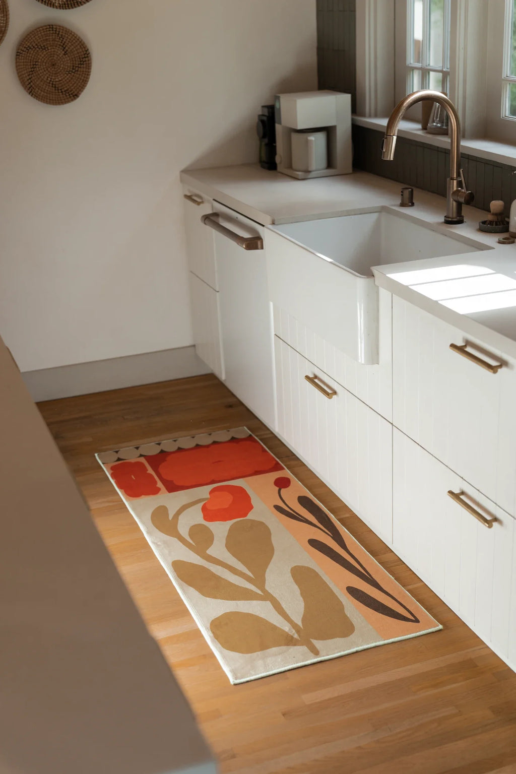 Floral runner rug in a bright bathroom vanity area with white cabinetry and a light wood floor
