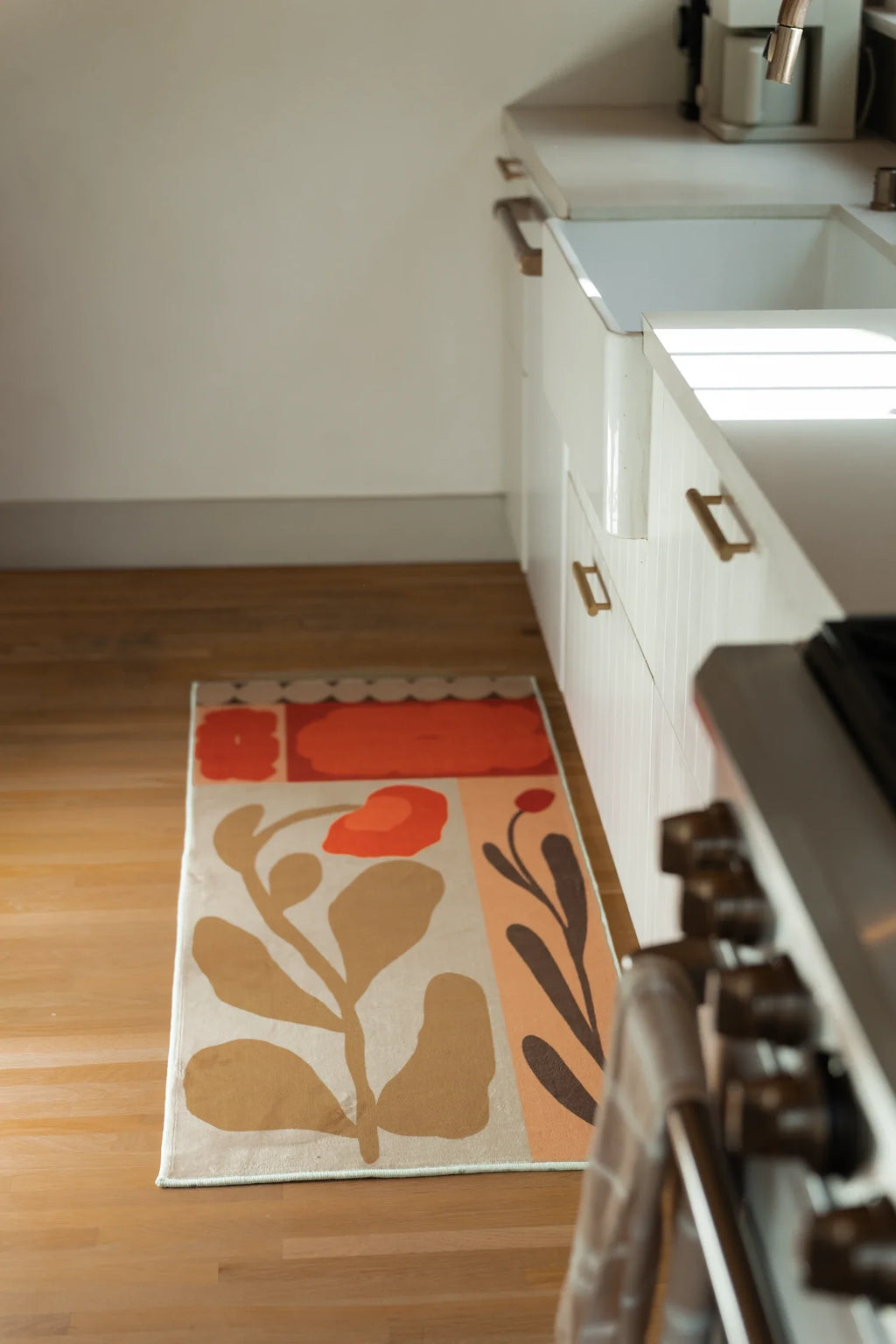 Long view of the patchwork flower rug in a kitchen walkway beside a white range and lower cabinets