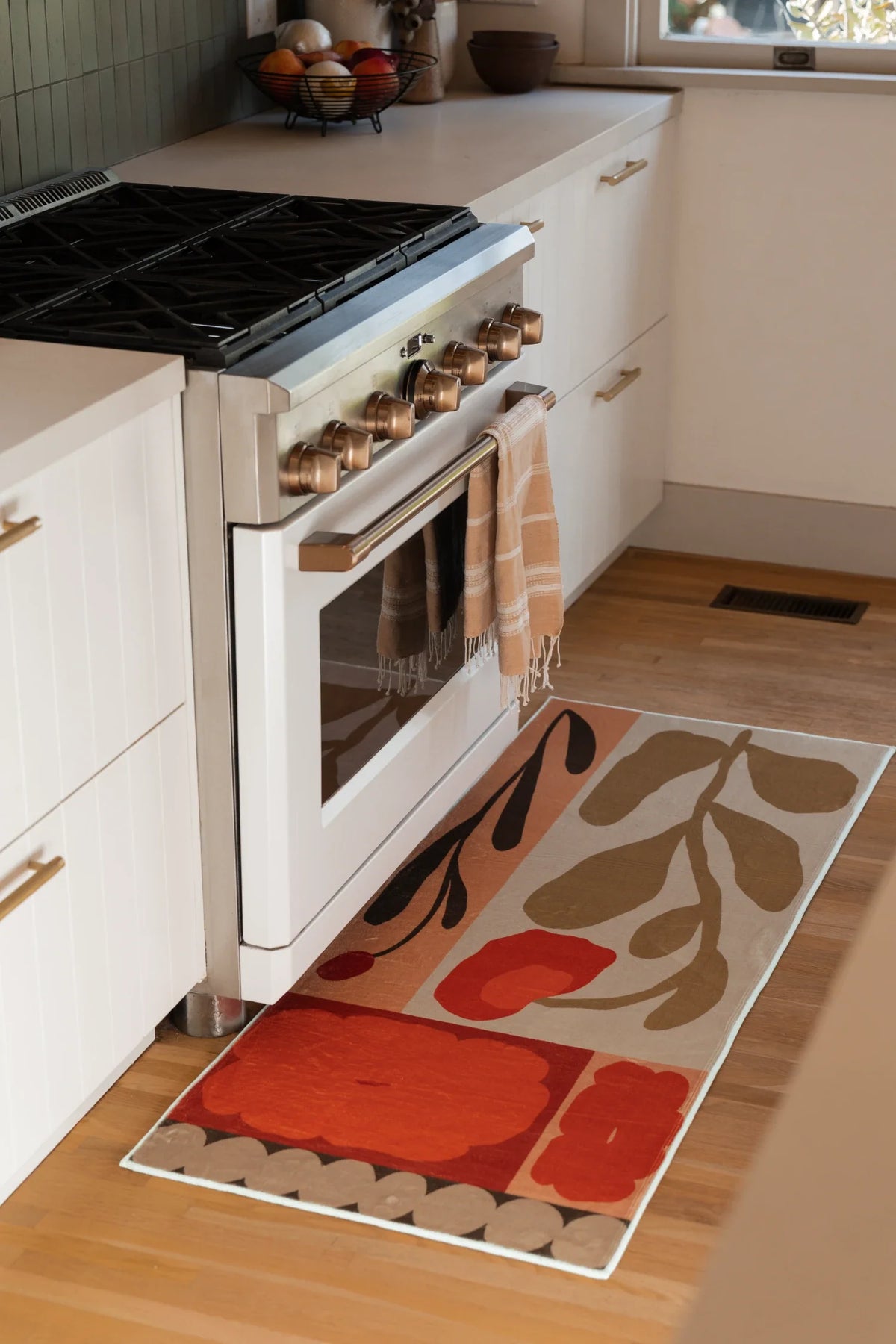 Rust Red Vintage Patchwork Floral Rug by Sophie Deller beside a white kitchen oven on a light wood floor