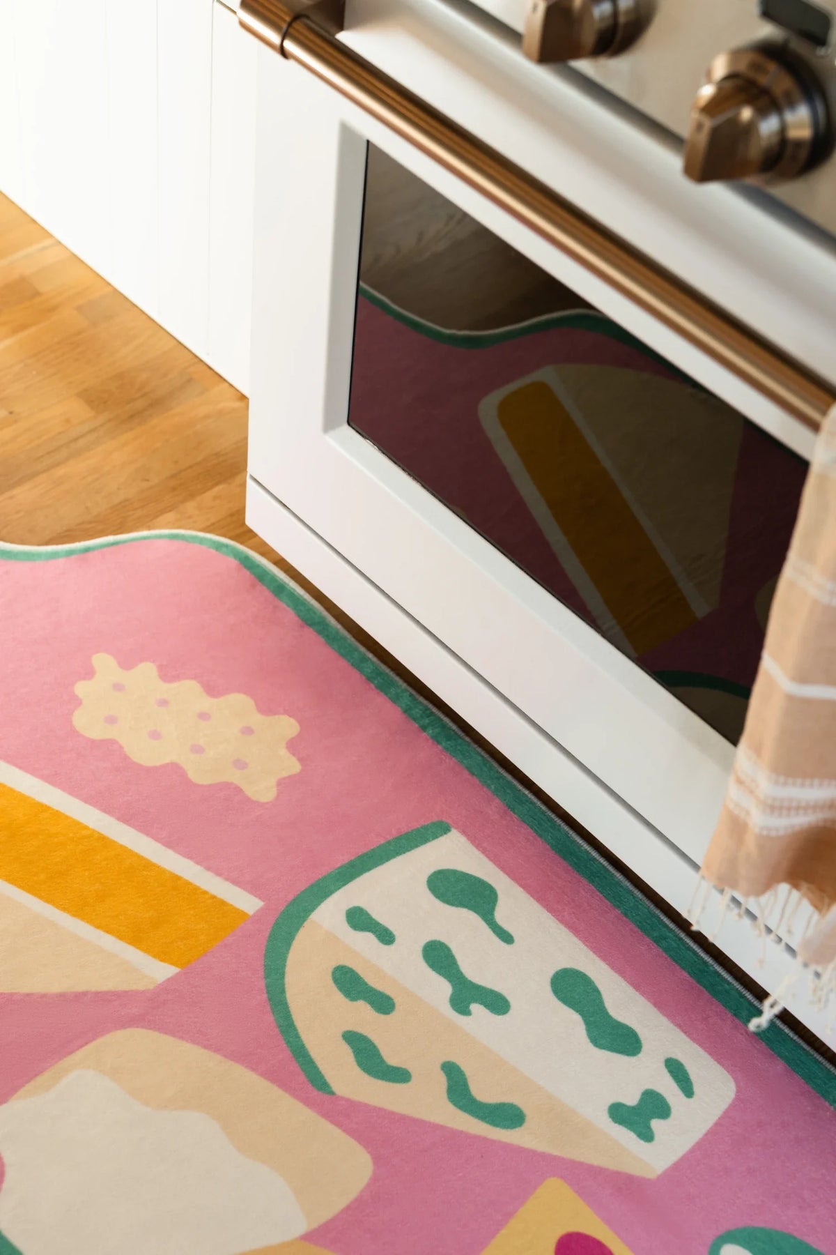 Close view of the graphic runner rug in a bright kitchen walkway, showing cheese, crackers, and dip shapes on a pink board