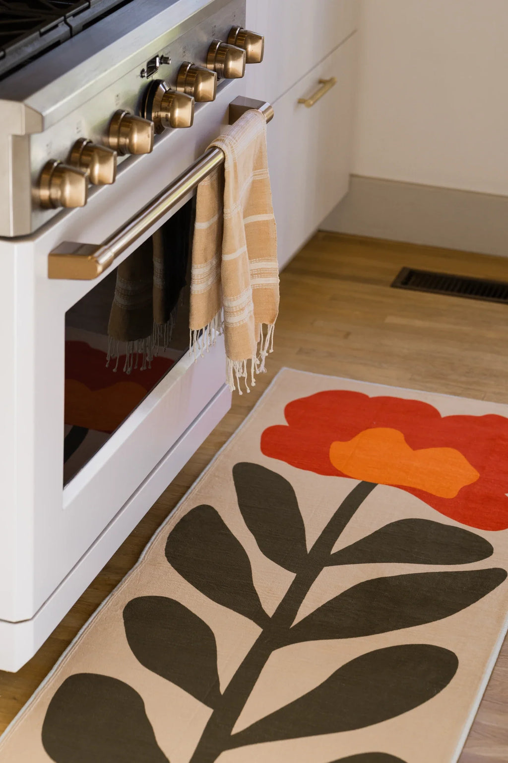 Vintage flower runner in a bright kitchen walkway with white cabinetry and a large black stem motif