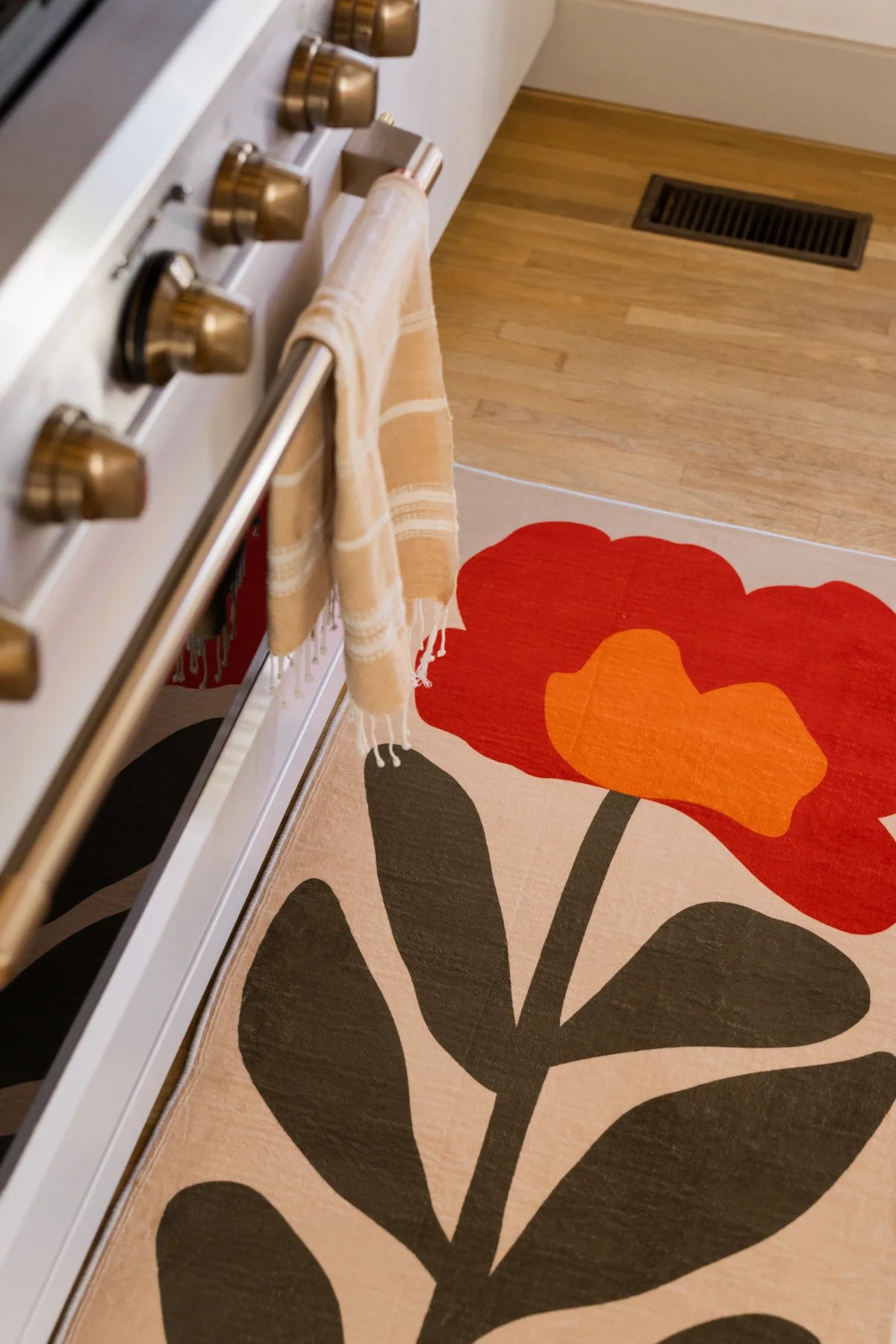Partial close up of the Red Vintage Flower Runner Rug beside the oven door, showing the red flower and dark stem