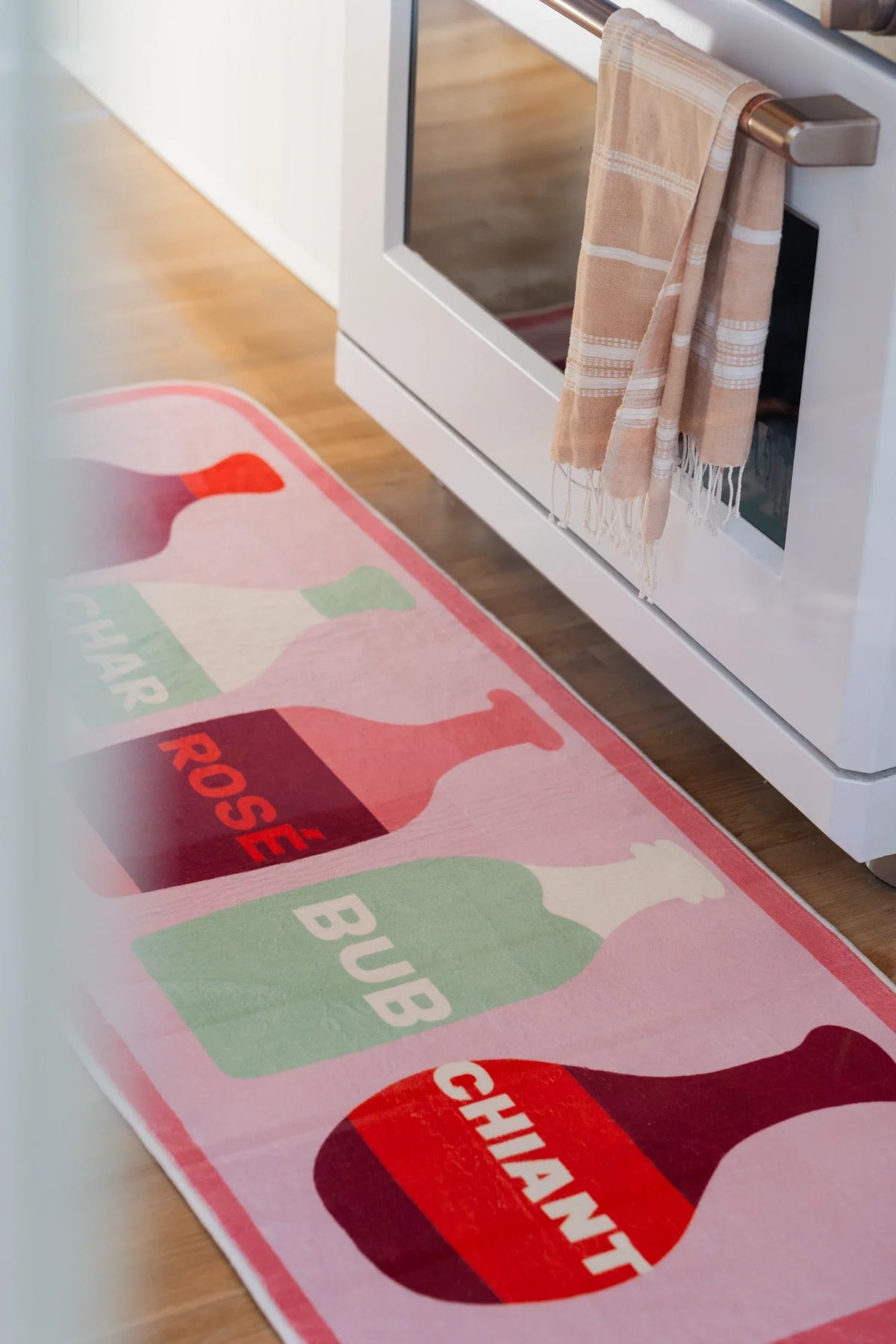 Close view of the wine bottle runner in a bright kitchen walkway, showing blush pink blocks and labeled bottle shapes