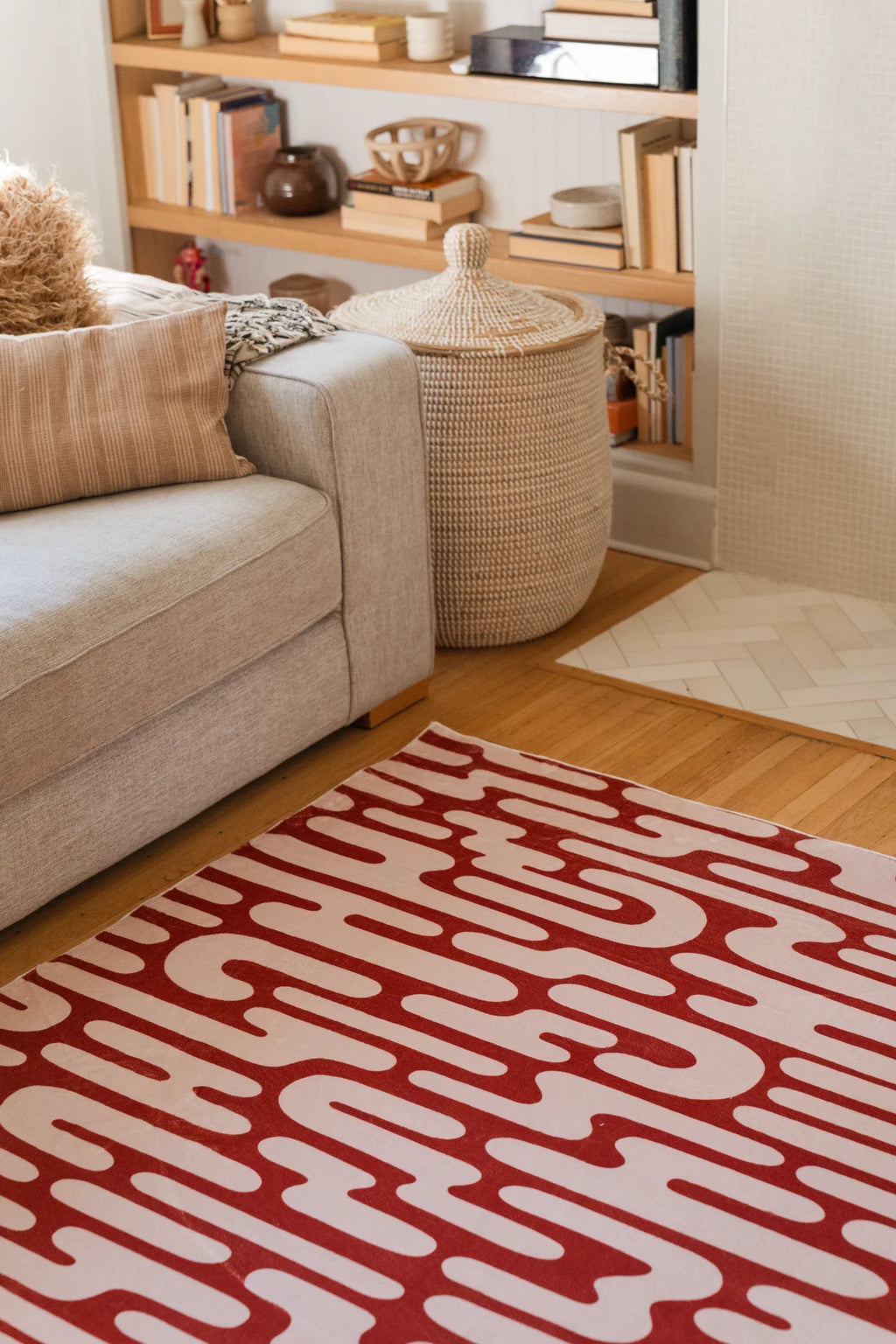 Brown Abstract Wavy Area Rug beside a cream sofa in a bright modern living room with open shelving