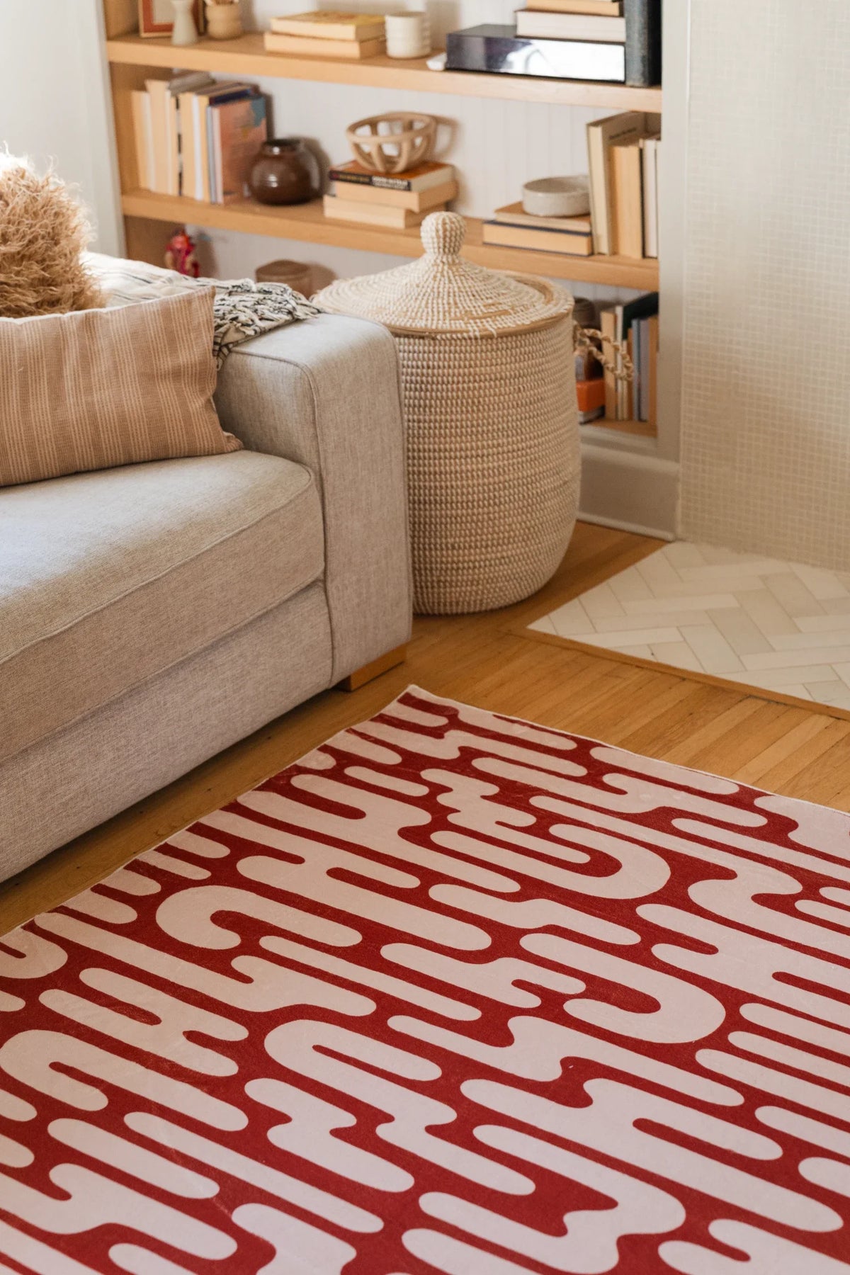 Brown Abstract Wavy Area Rug beside a cream sofa in a bright modern living room with open shelving