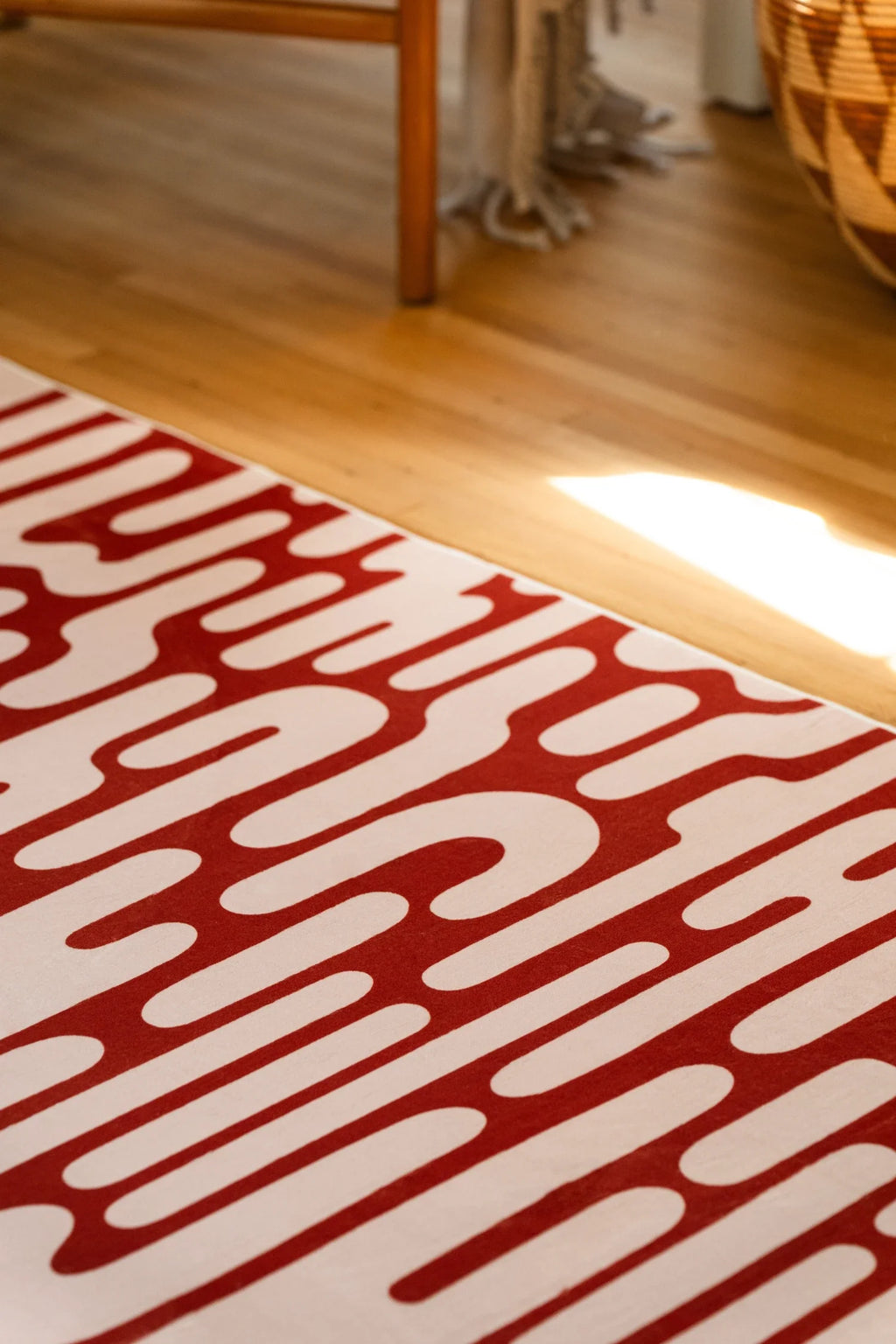 Close view of the brown Abstract Wavy Area Rug on a light wood floor with sunlight along one corner