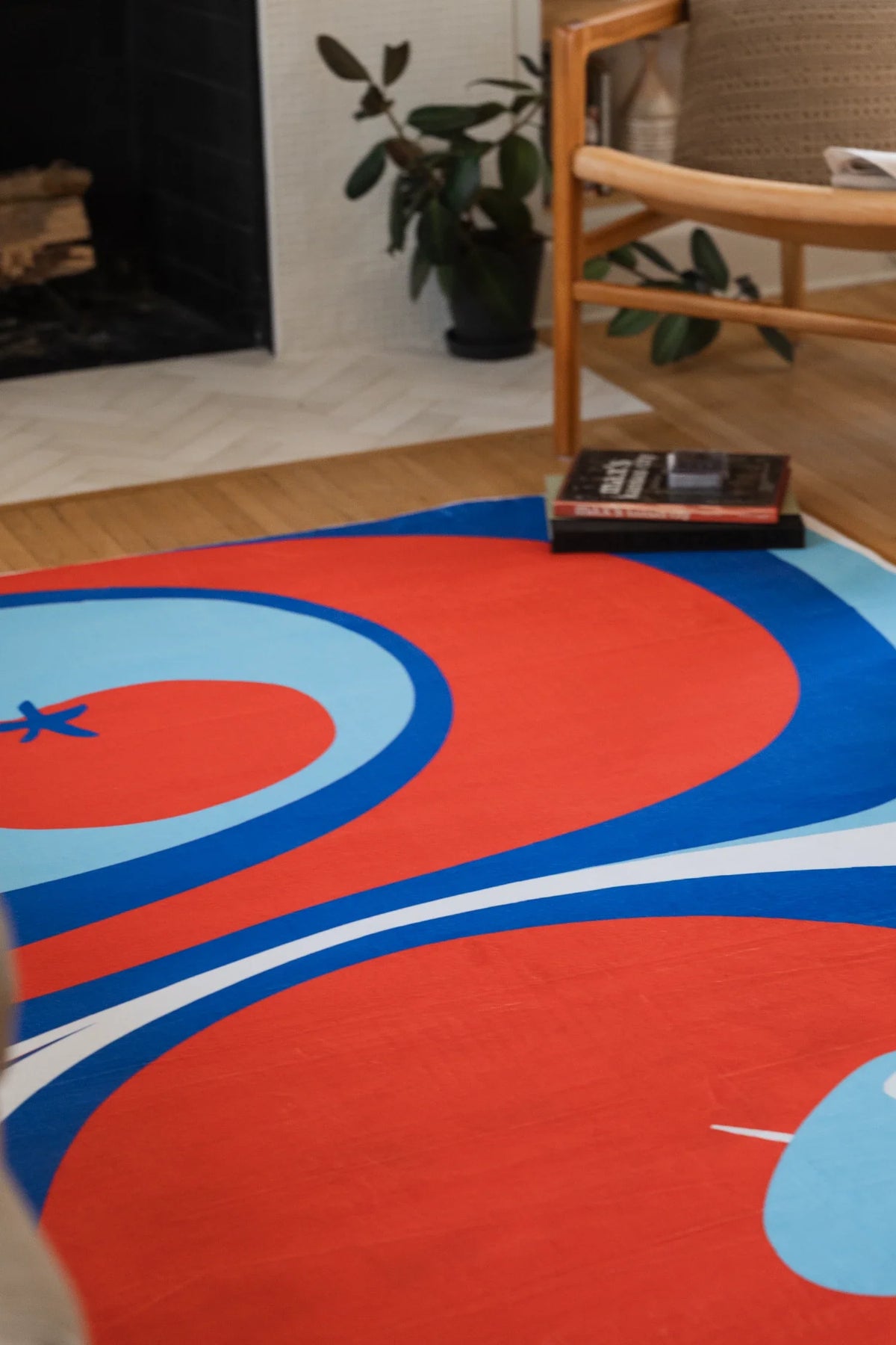 Blue and red rug near a fireplace and wood chair, showing a red tomato circle and pale blue curved bands