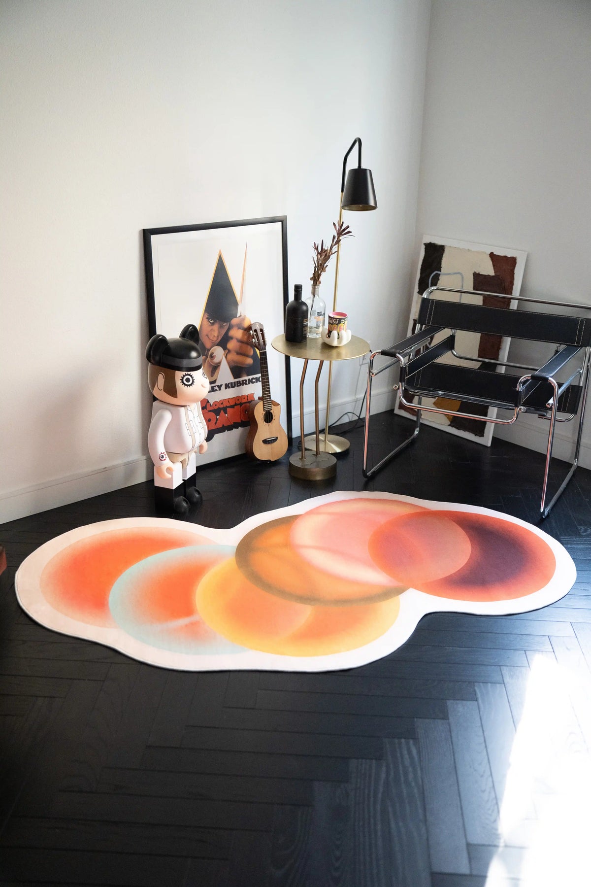 Earth Tone Abstract Circle Rug by Juan Marquez in a modern reading corner with a chrome chair, guitar, framed art, and floor lamp