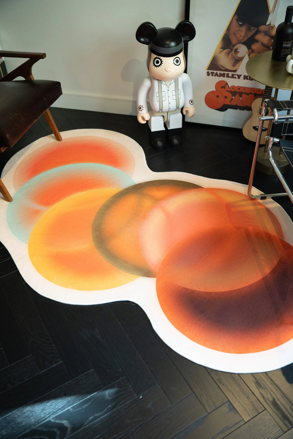 Close view of the Earth Tone rug with overlapping orange and brown circles beside a guitar and decorative figure