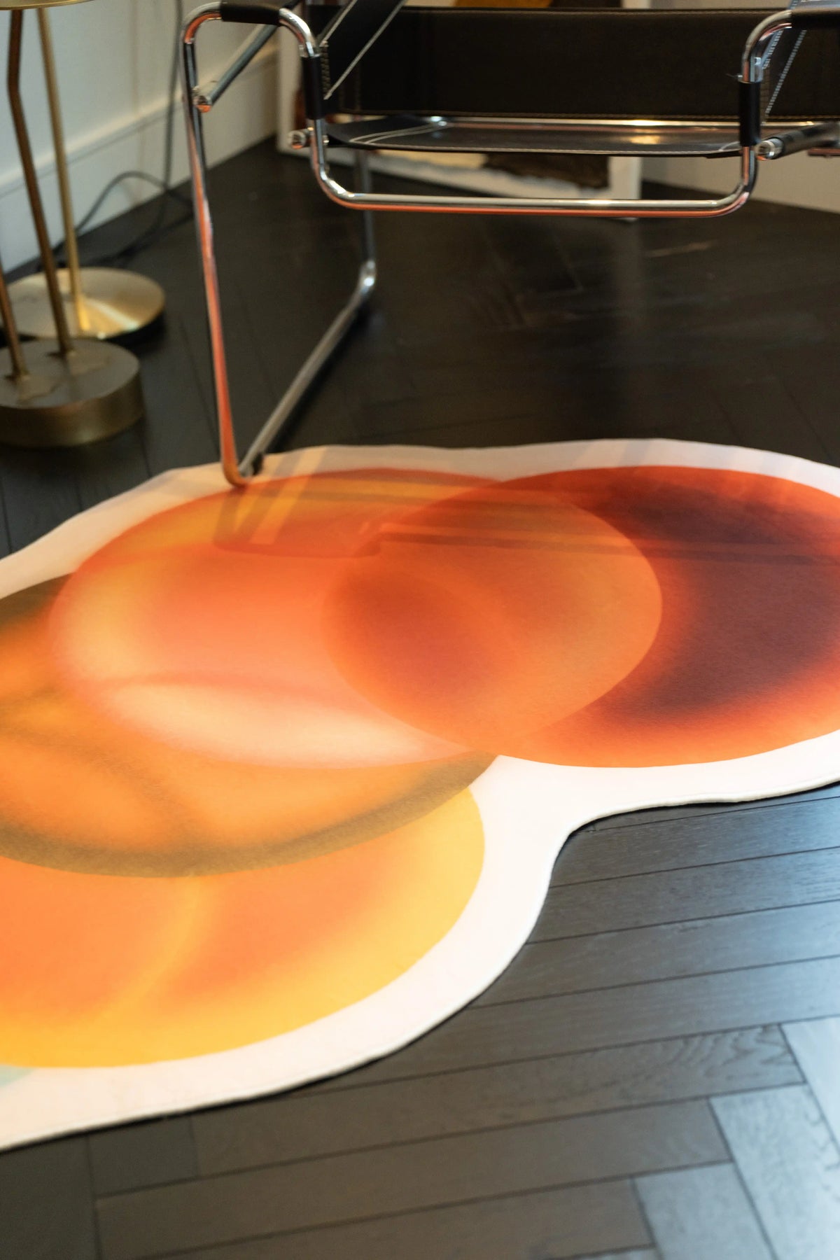 Juan Marquez abstract circle rug under a chrome chair with overlapping earth tone circles and a soft white border