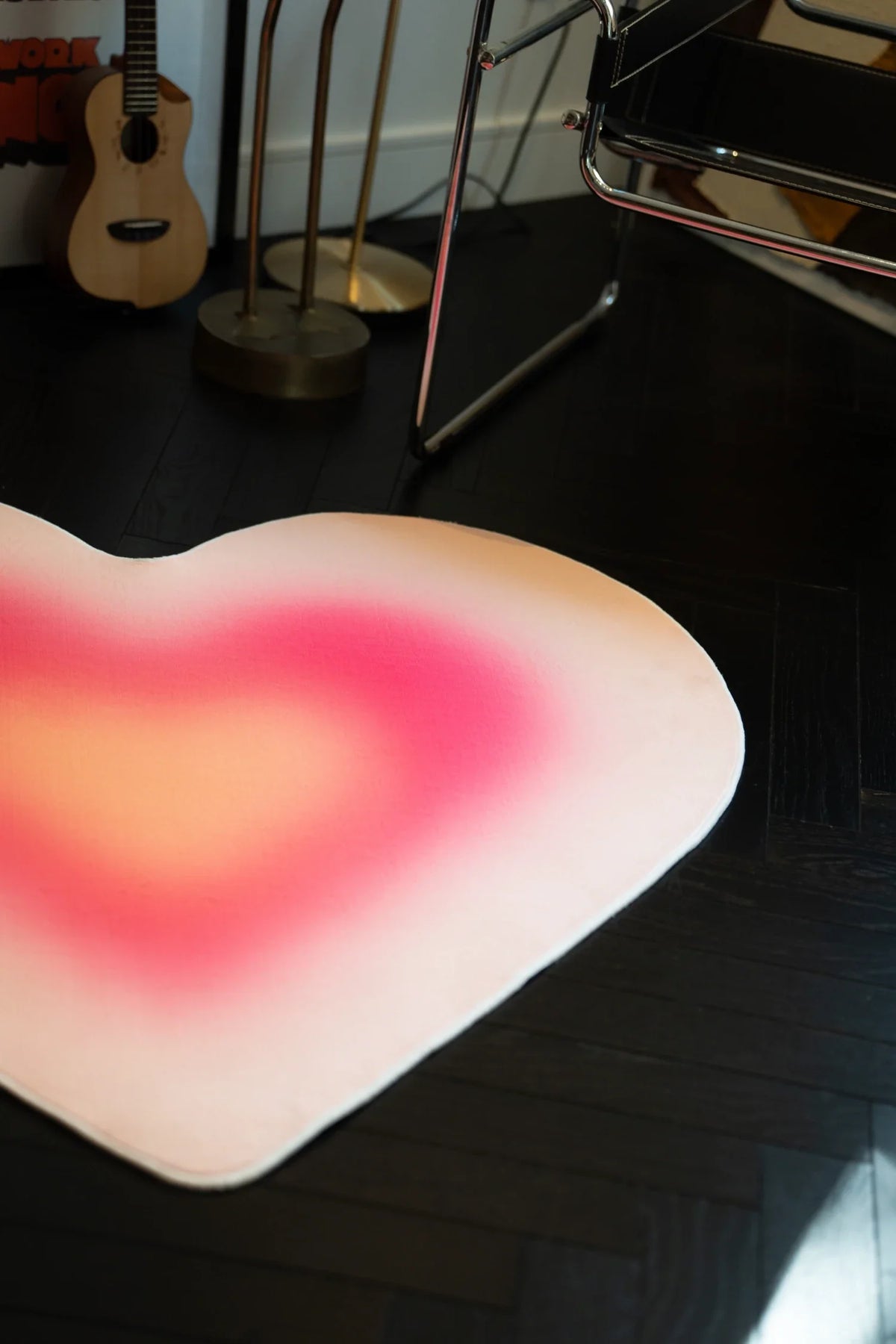 Pink heart rug with soft yellow and magenta gradients beside a chrome chair and guitar